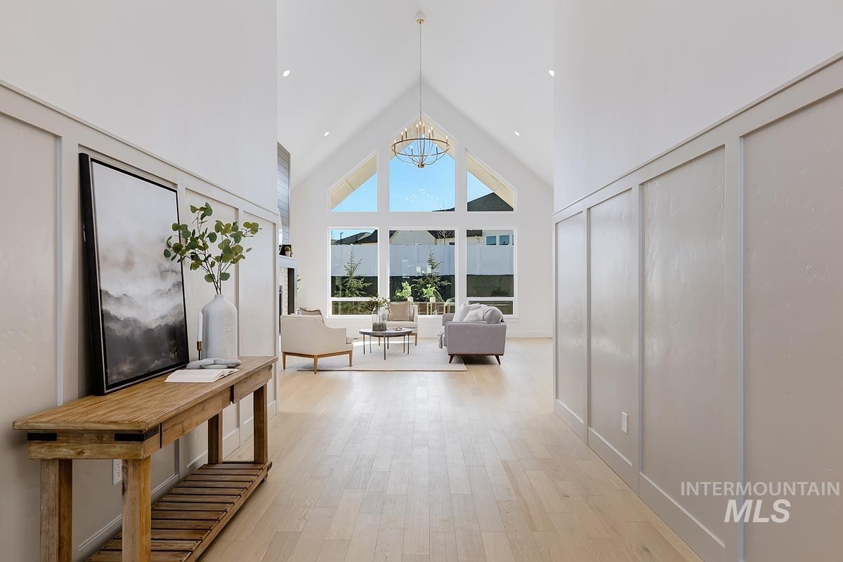 Bedroom featuring high vaulted ceiling, light wood finished floors, and a chandelier