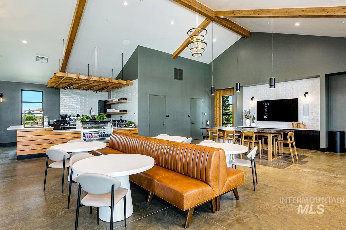 Living room with beam ceiling, concrete floors, high vaulted ceiling, plenty of natural light, and a chandelier