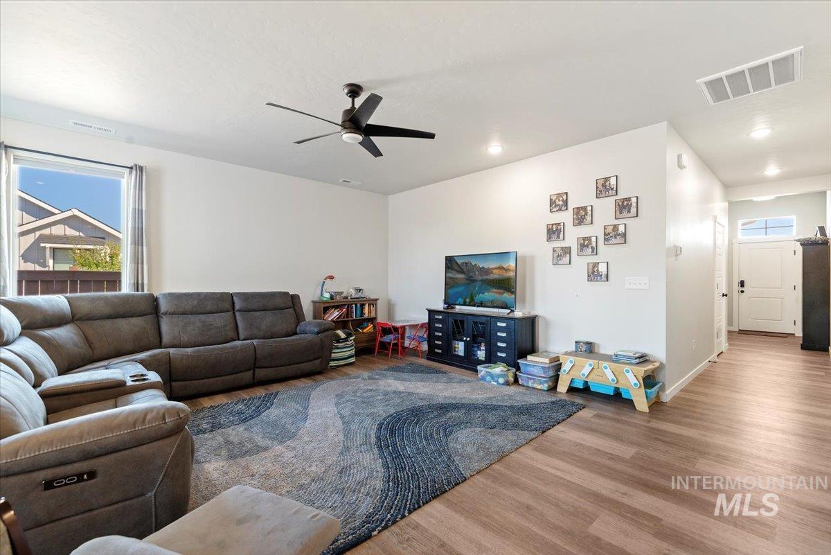 Living room featuring healthy amount of natural light, wood finished floors, a ceiling fan, and recessed lighting