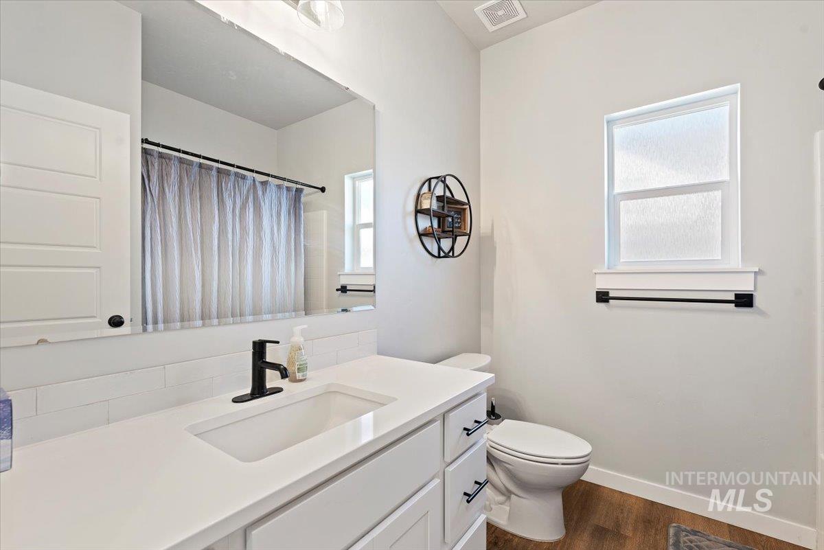 Full bath featuring dark wood finished floors, vanity, and a shower with shower curtain