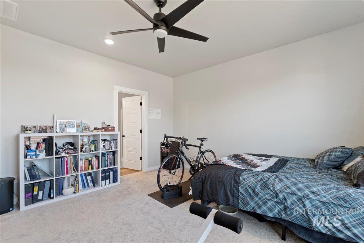 Carpeted bedroom with a ceiling fan and recessed lighting