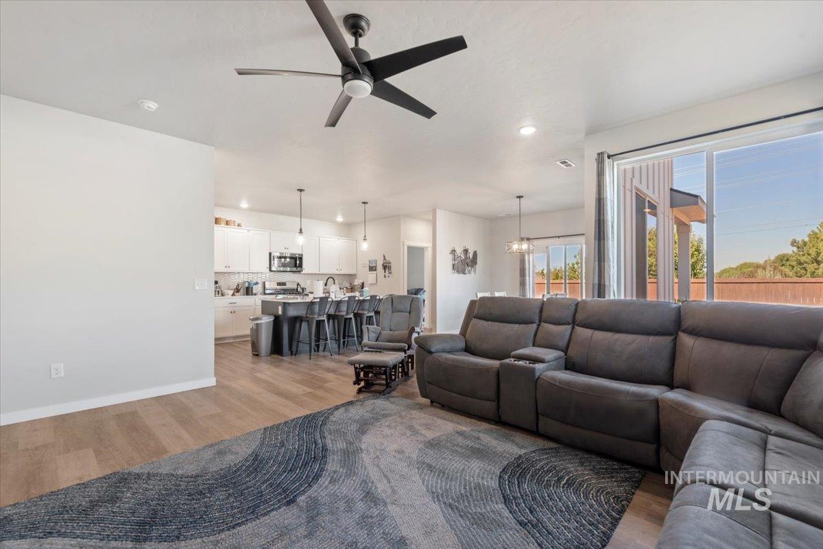 Living room with a ceiling fan, light wood finished floors, and recessed lighting