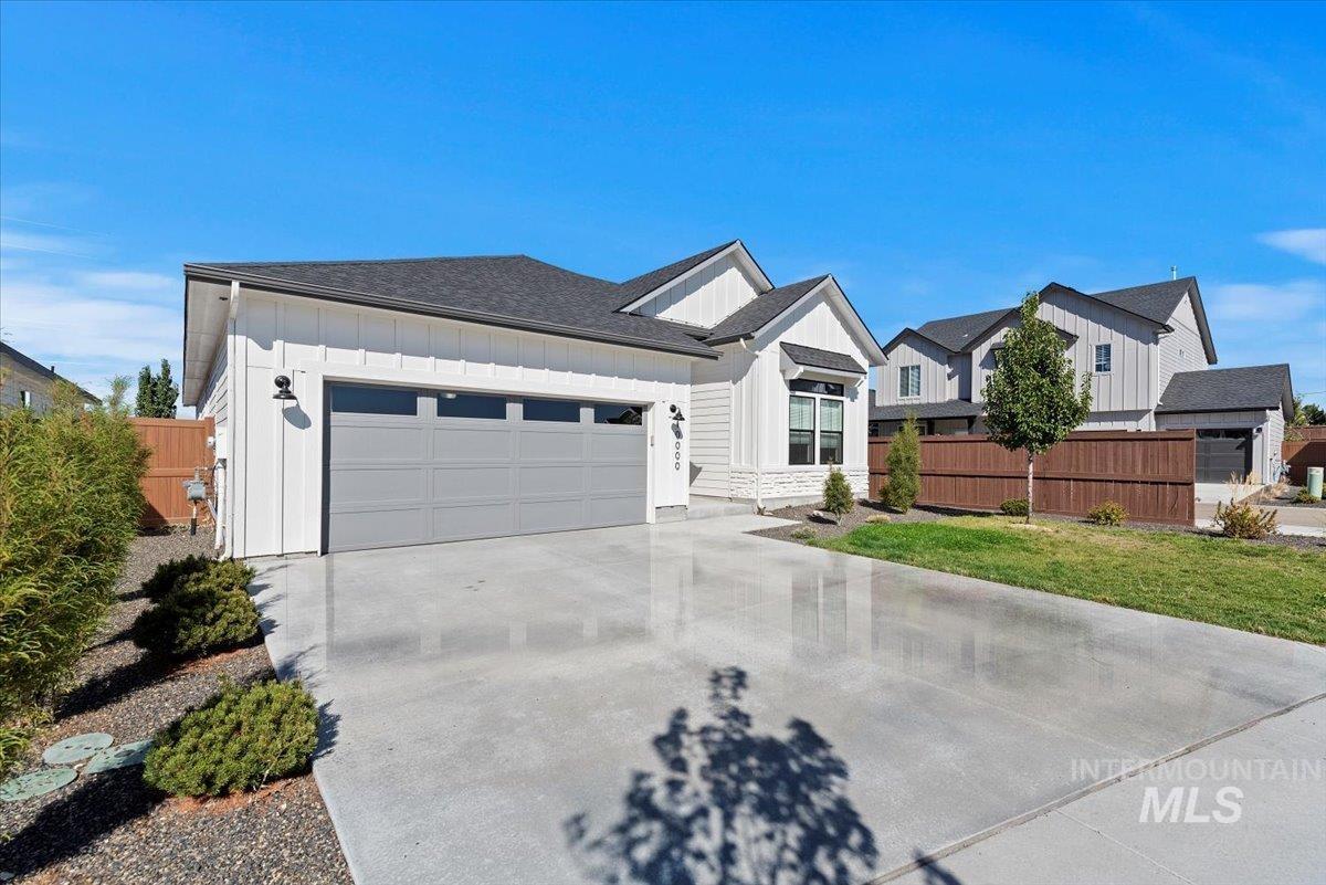 Modern farmhouse featuring board and batten siding, concrete driveway, a garage, and roof with shingles