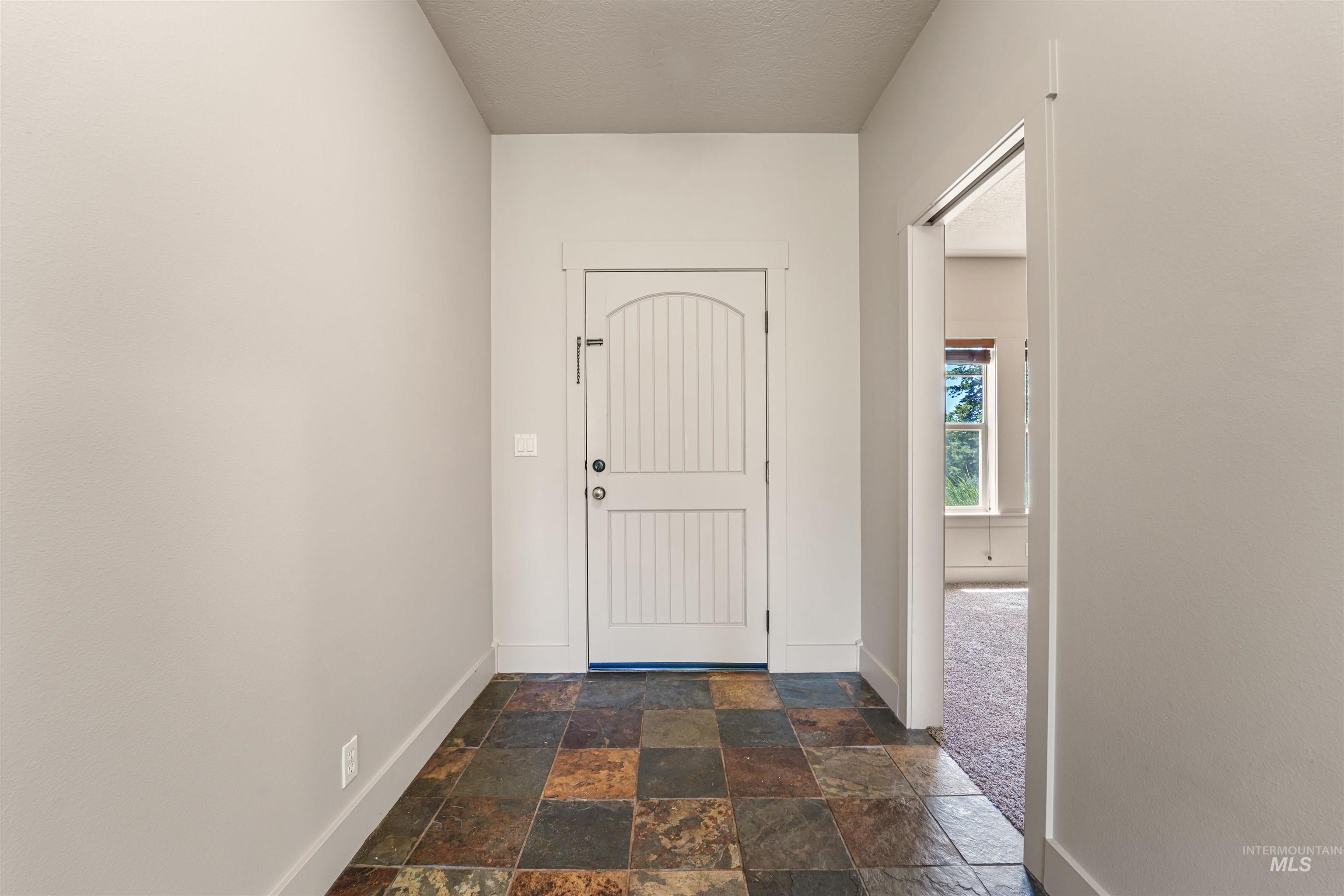 Foyer entrance with baseboards and stone tile flooring