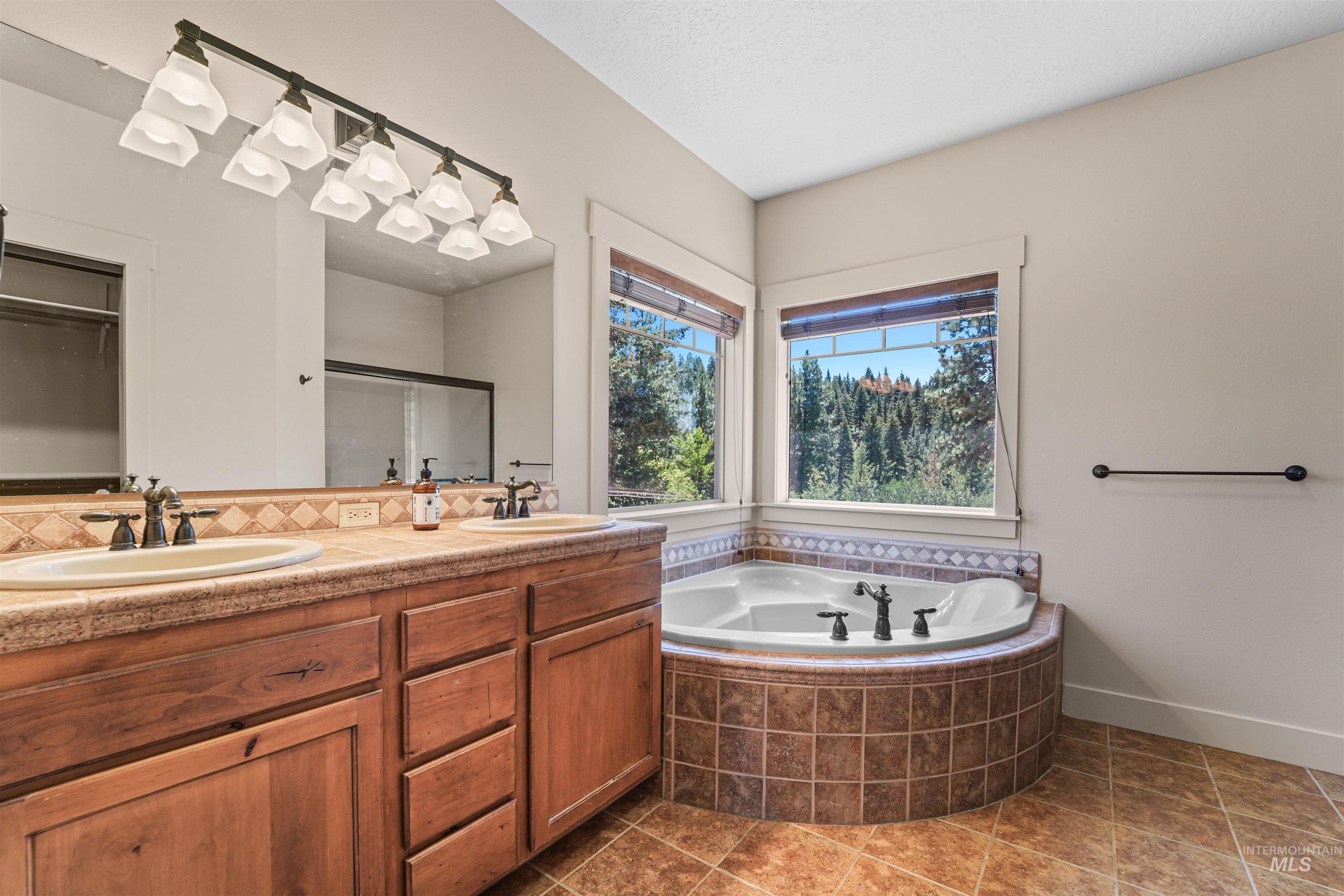 Bathroom featuring a garden tub, double vanity, a shower stall, and tasteful backsplash