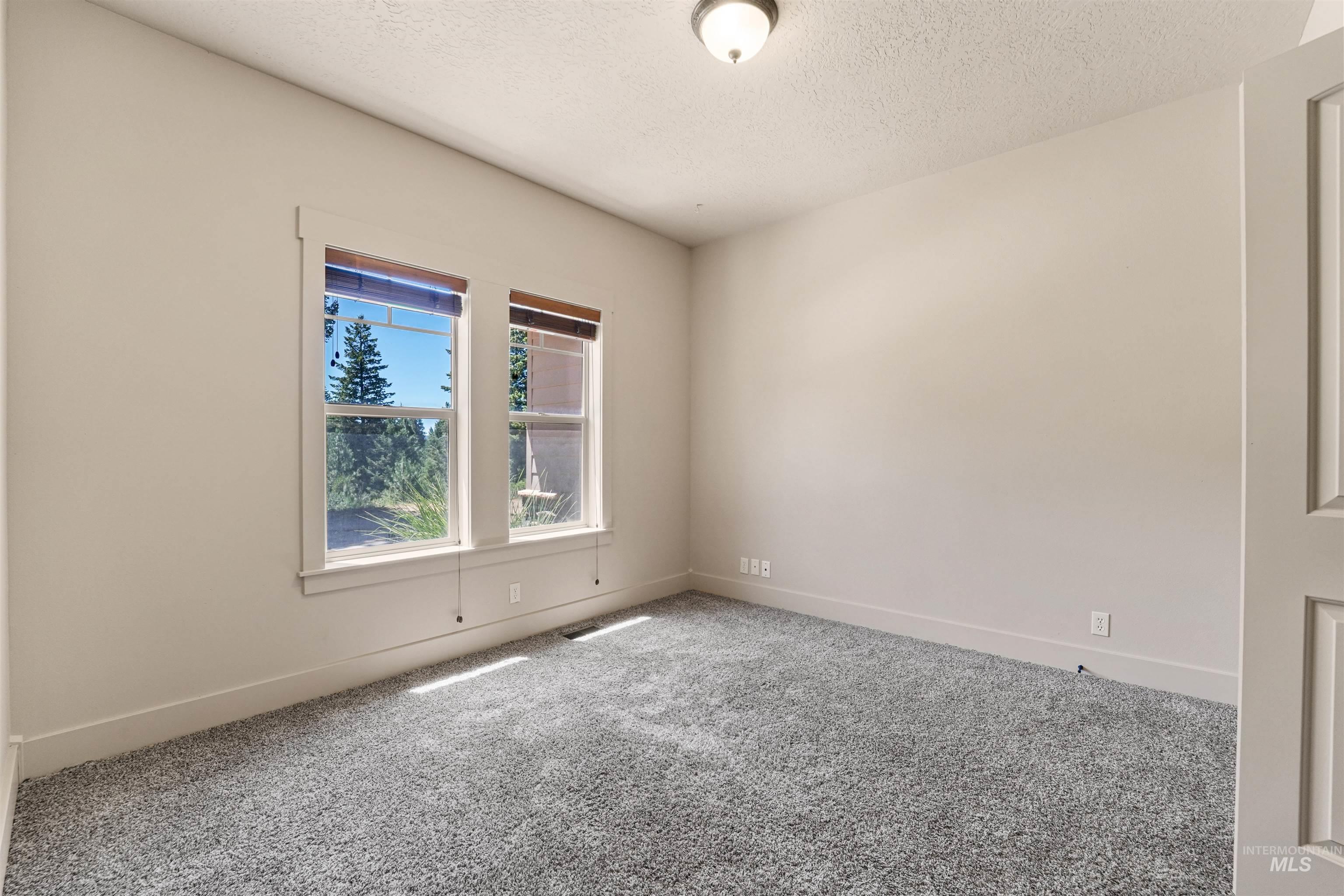 Empty room with carpet floors and a textured ceiling