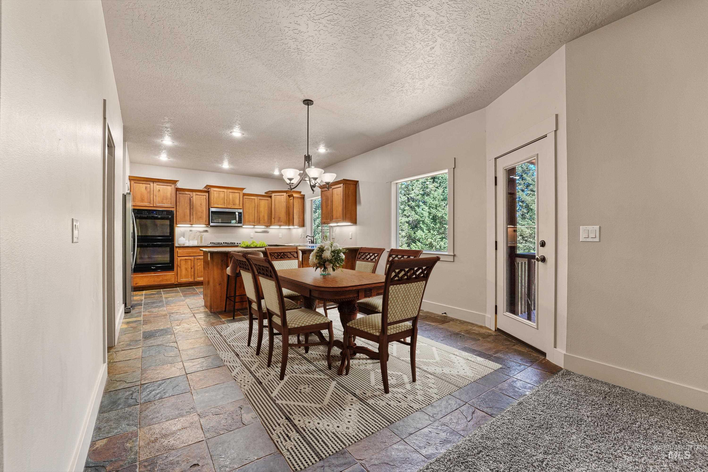Dining room featuring stone tile floors, a chandelier, and a textured ceiling