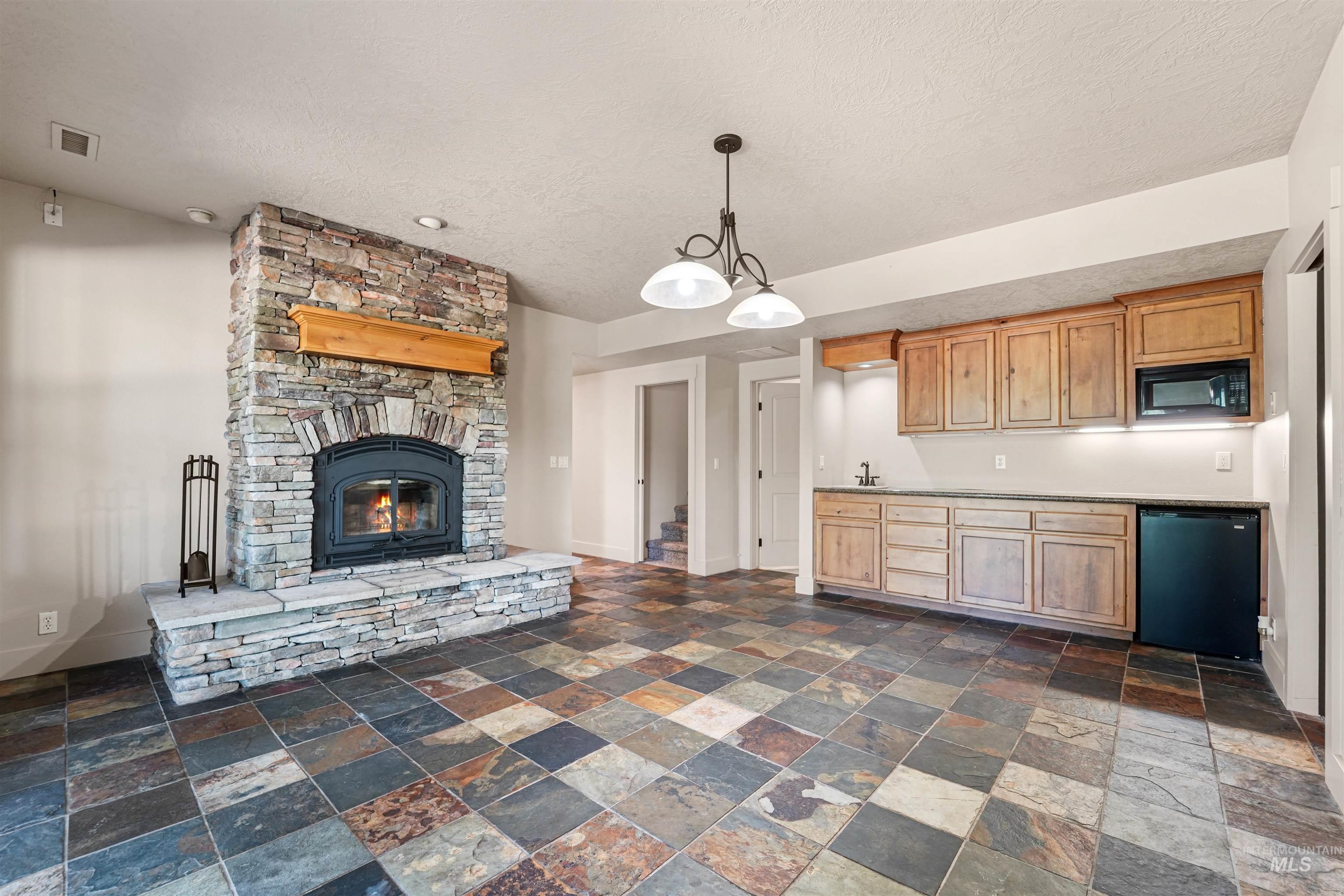 stone tile floors, a textured ceiling, dishwashing machine, and a fireplace