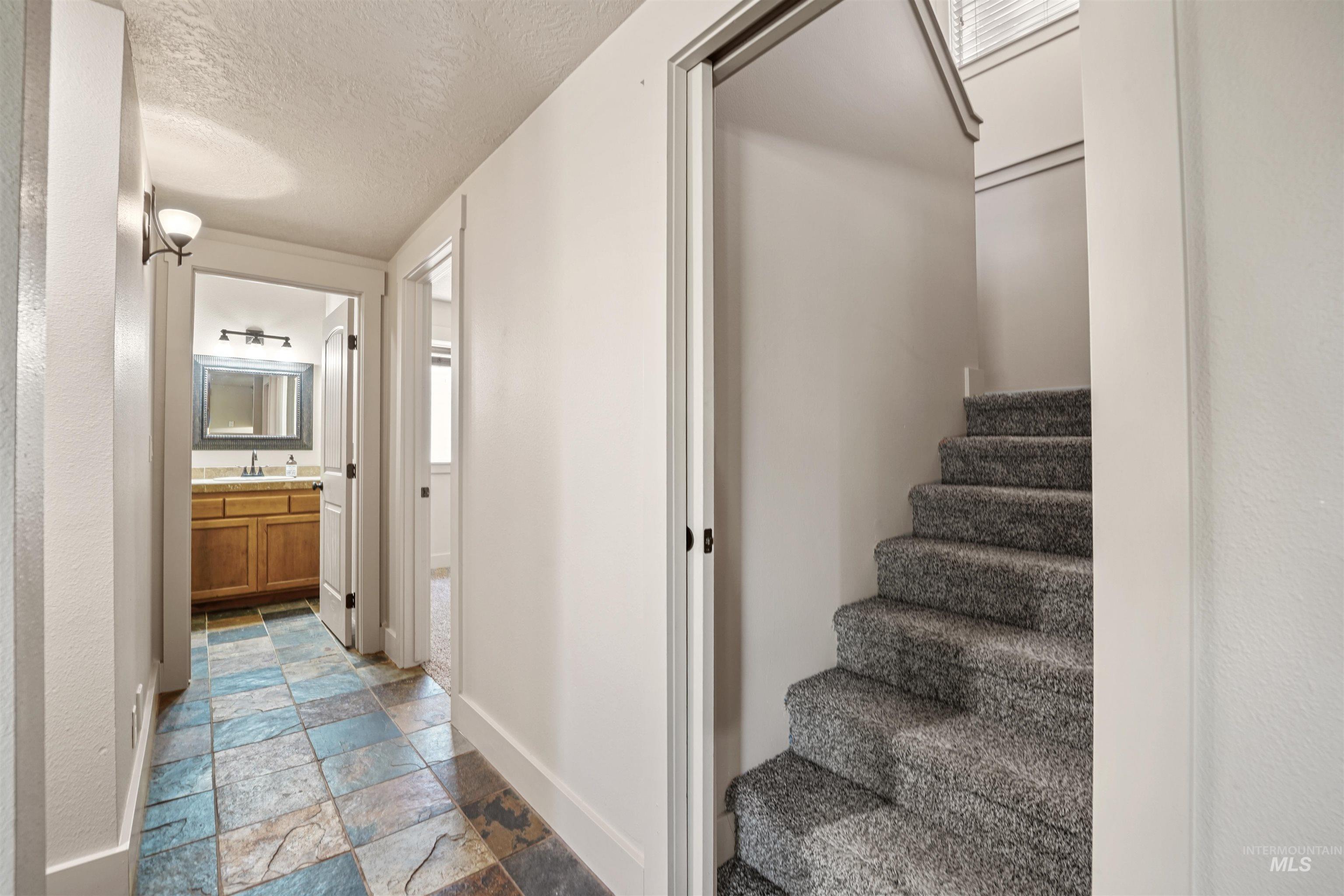 Staircase featuring stone tile flooring and a textured ceiling