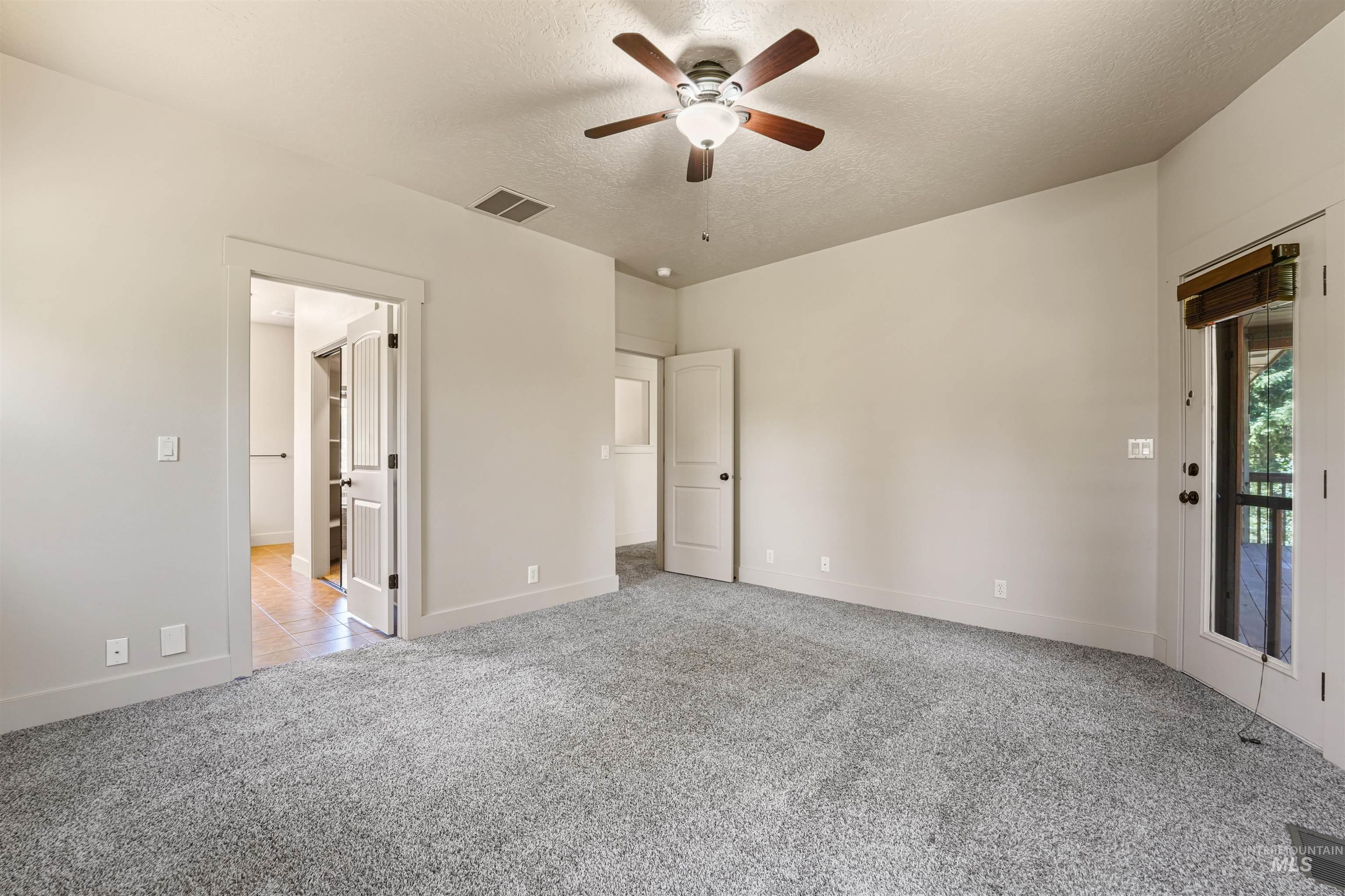 Carpeted spare room featuring a ceiling fan and a textured ceiling