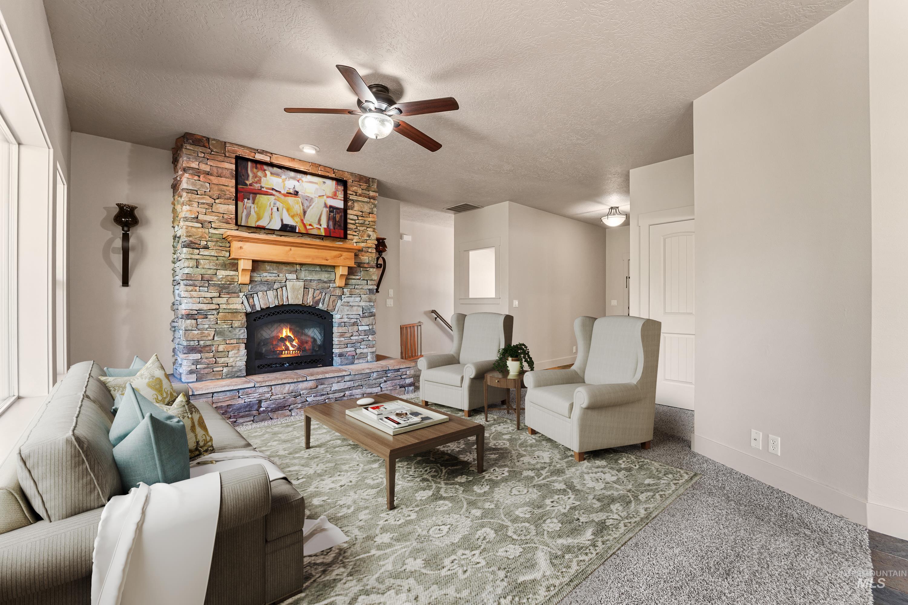 Living room featuring a ceiling fan, a textured ceiling, and a stone fireplace