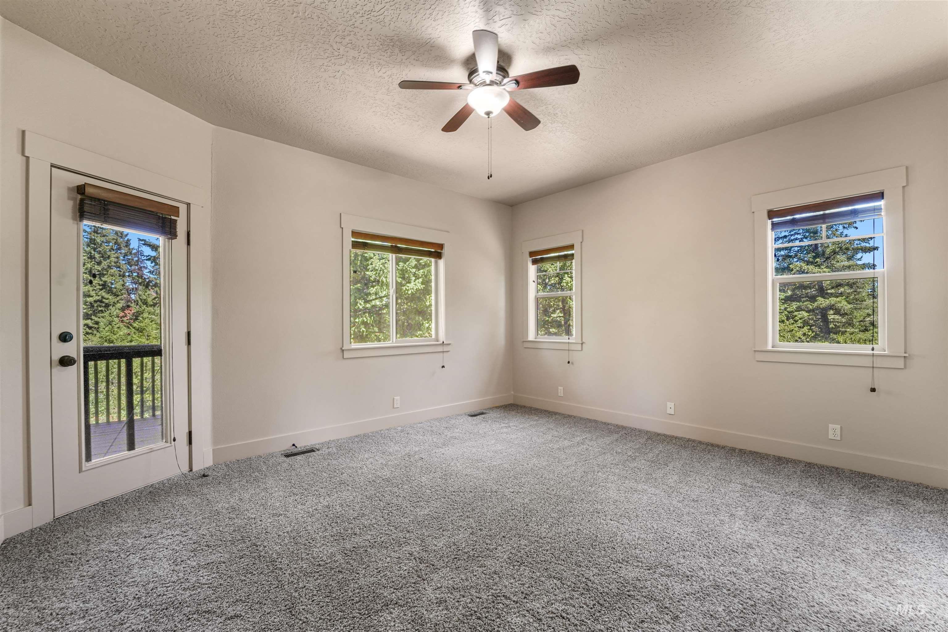 Empty room featuring a textured ceiling, a ceiling fan, and carpet floors