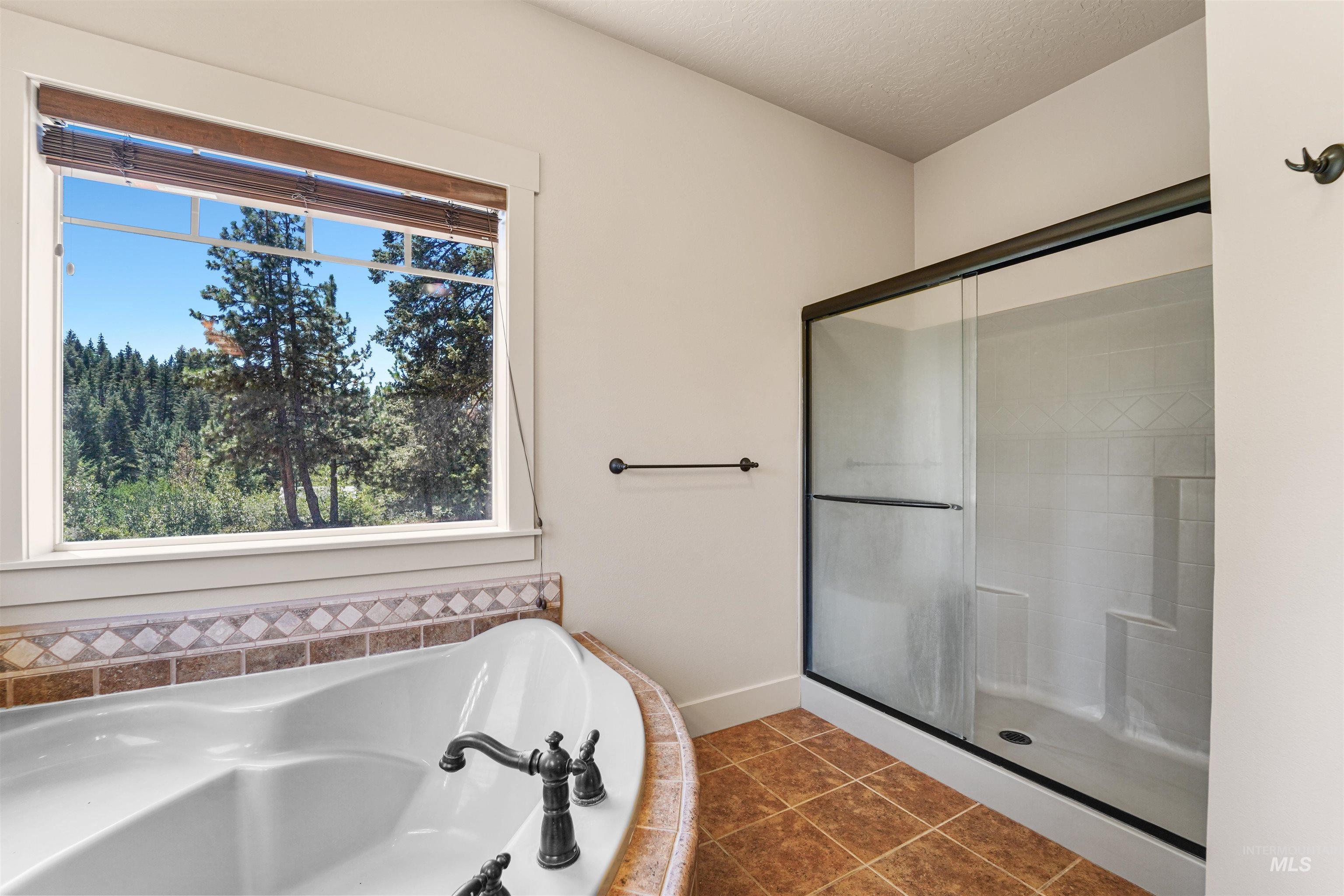 Bathroom featuring plenty of natural light, a bath, a stall shower, tile patterned floors, and a textured ceiling