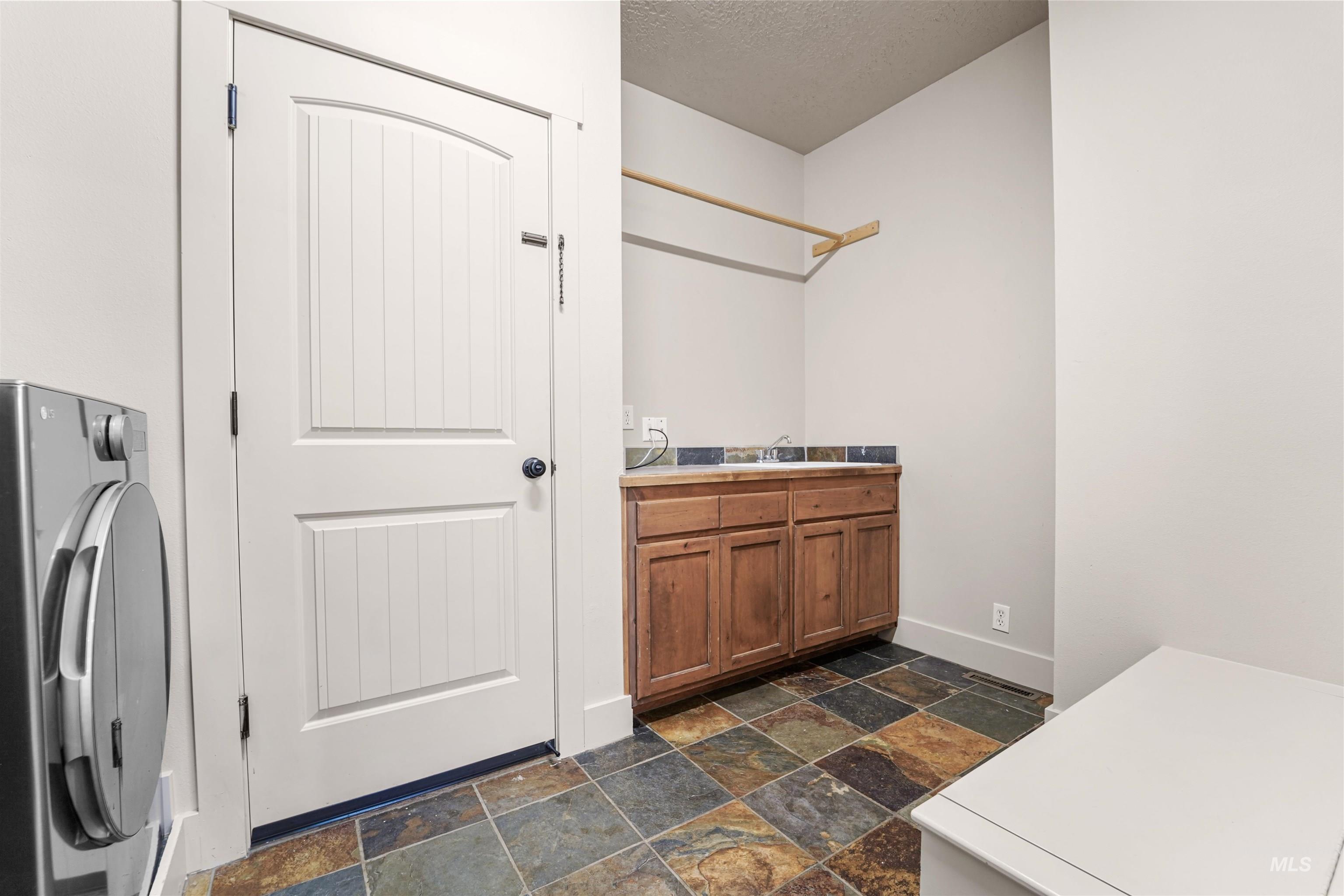Washroom with washer / clothes dryer, stone tile flooring, and a textured ceiling