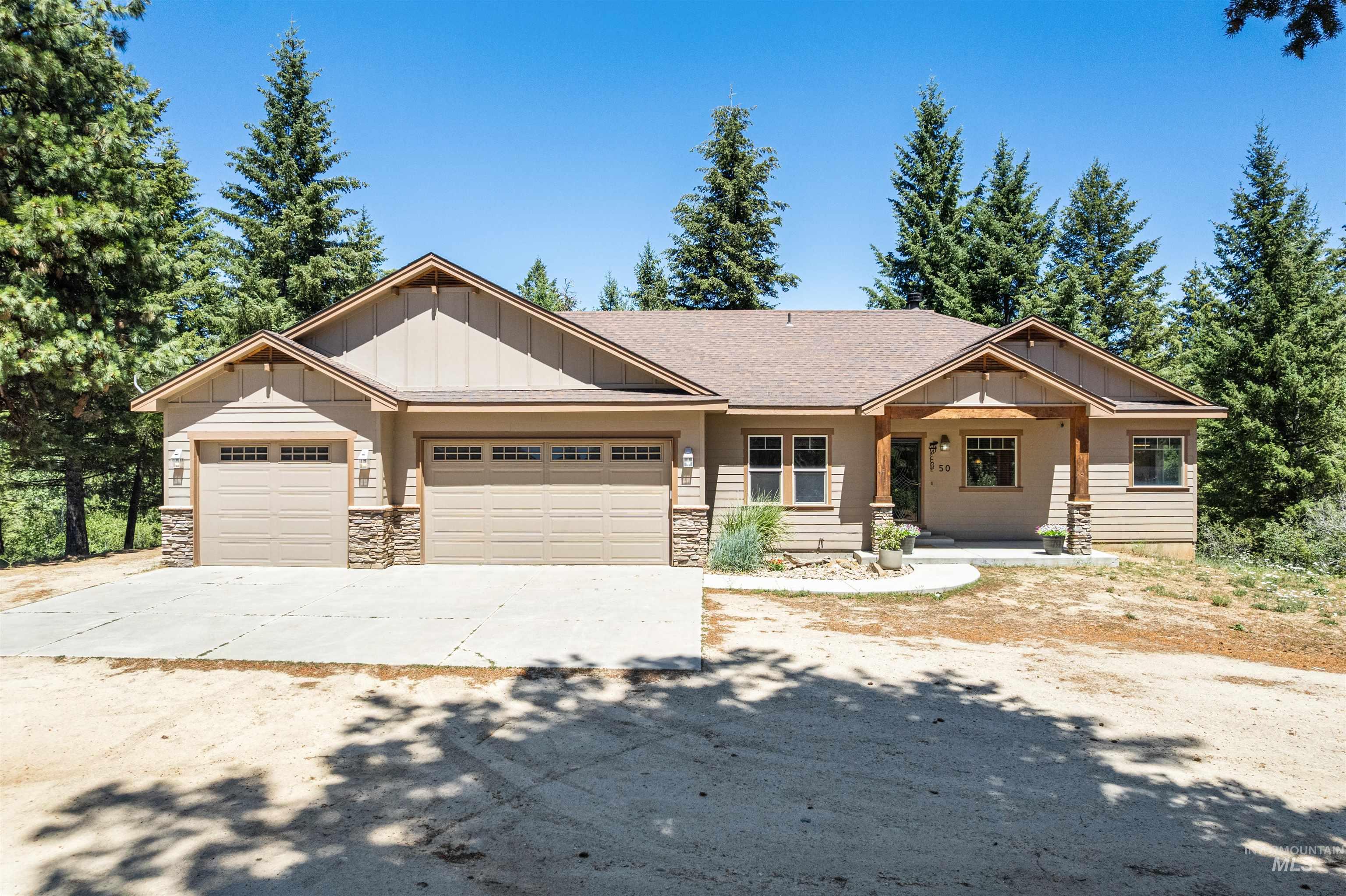 Craftsman house with board and batten siding, concrete driveway, a garage, stone siding, and a shingled roof