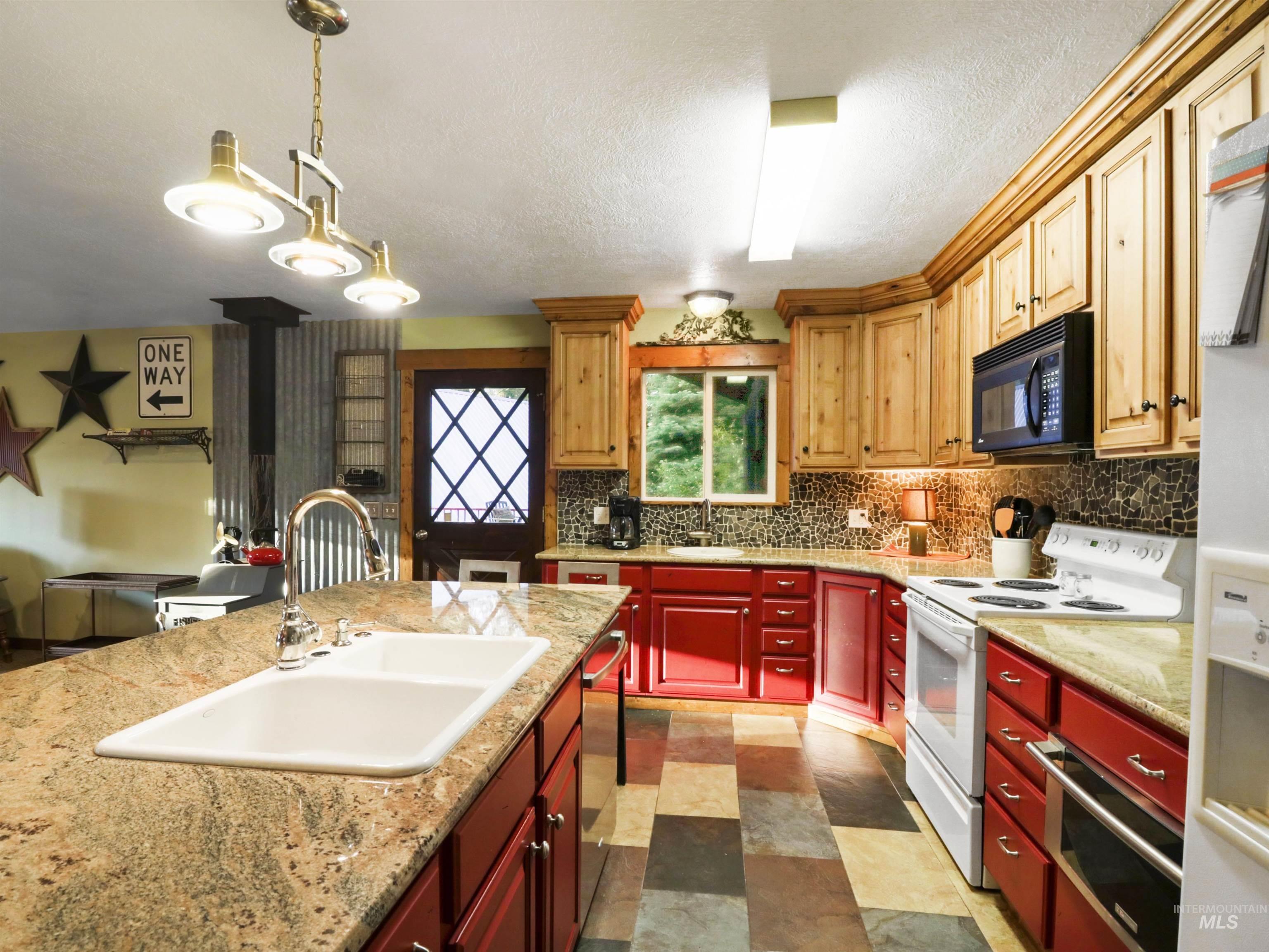 Kitchen featuring white appliances, decorative backsplash, light countertops, a textured ceiling, and open floor plan