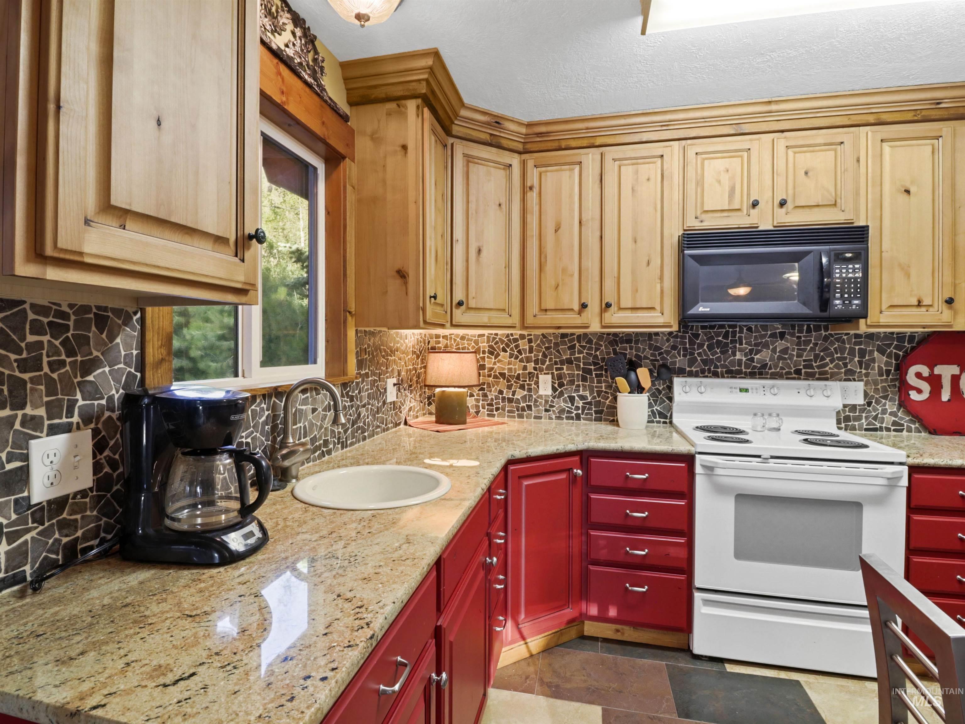 Kitchen featuring white electric range, black microwave, and backsplash