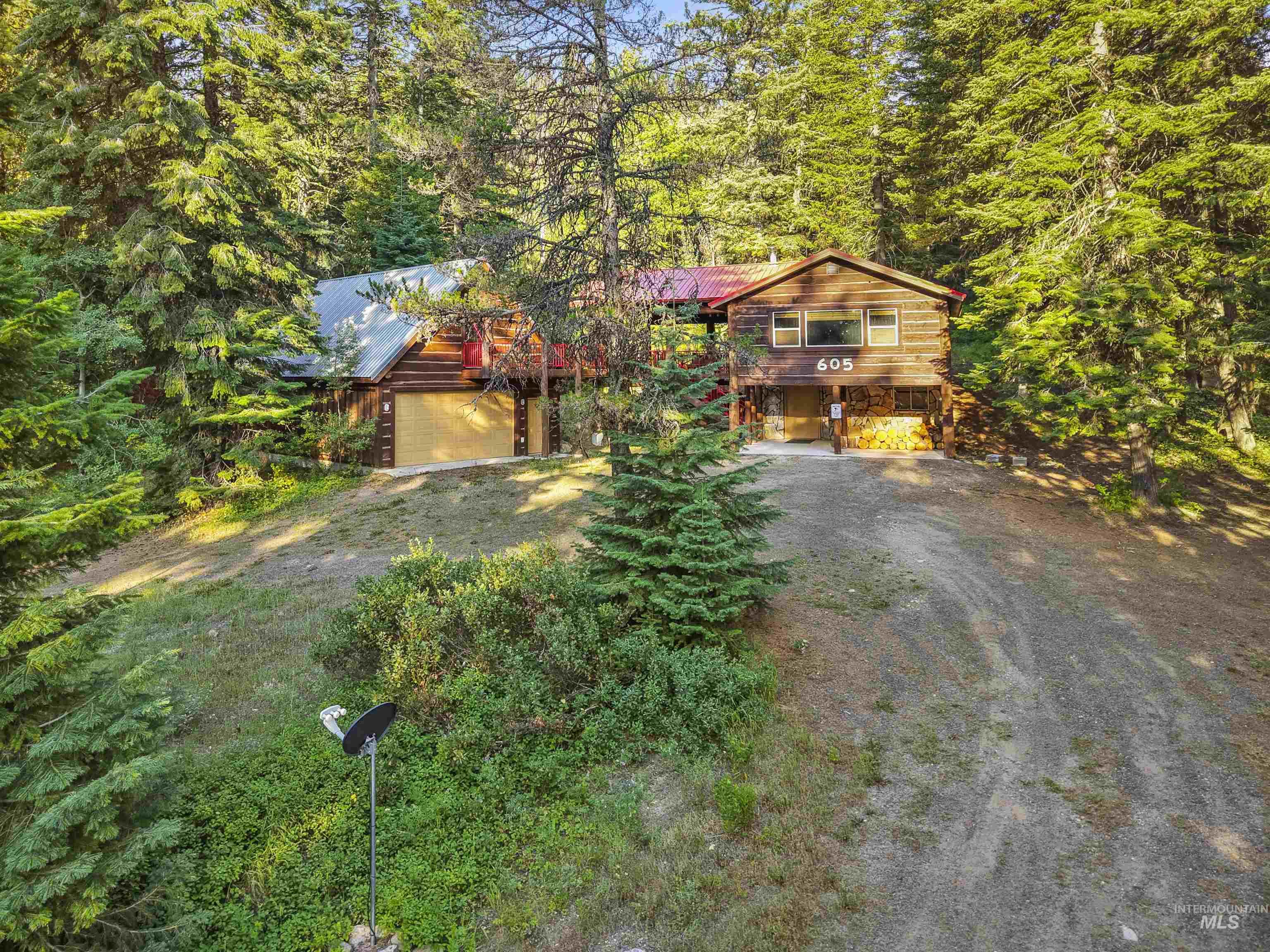 Chalet / cabin with driveway, a wooded view, a metal roof, and a carport