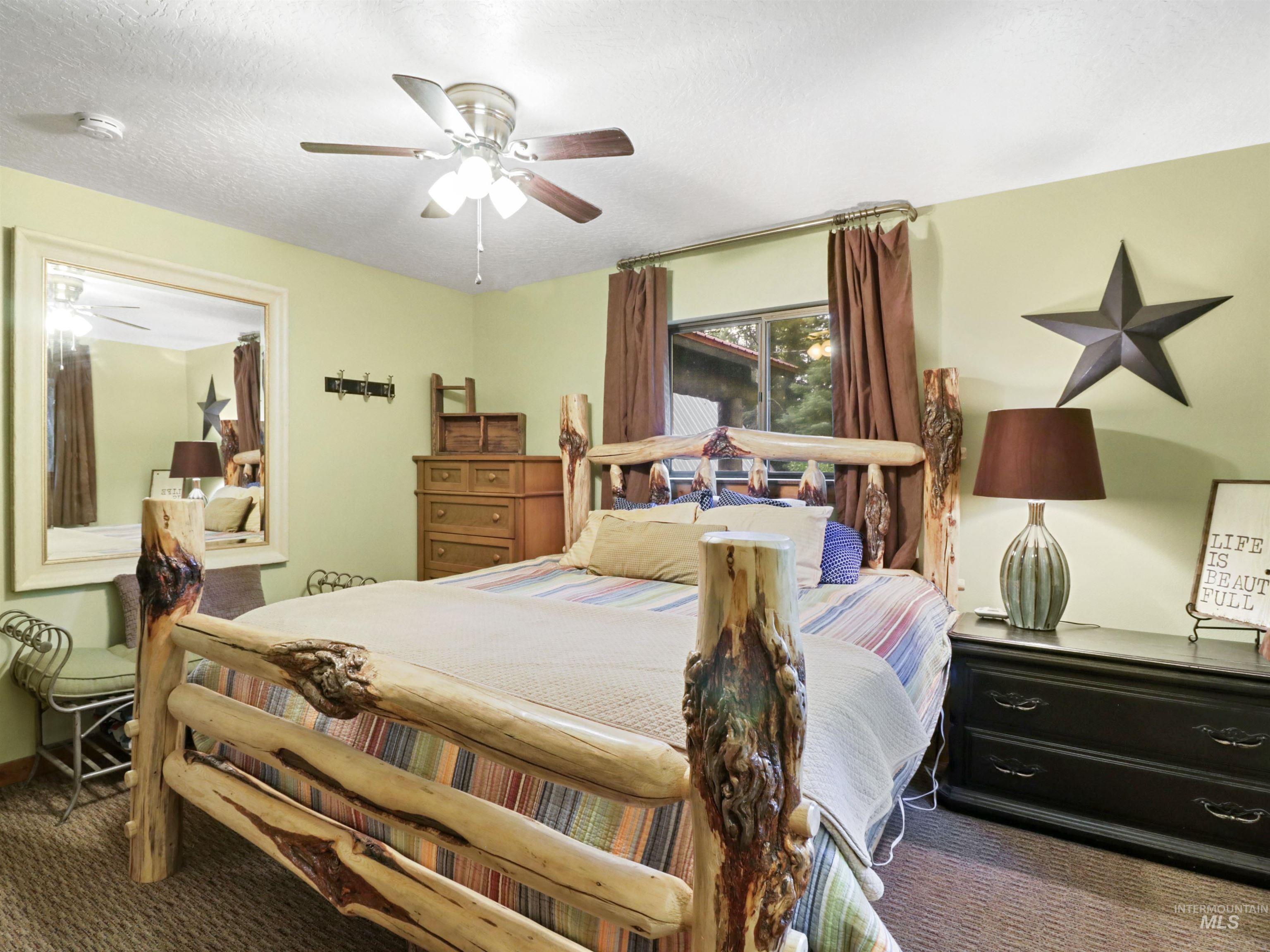 Carpeted bedroom featuring a textured ceiling and a ceiling fan