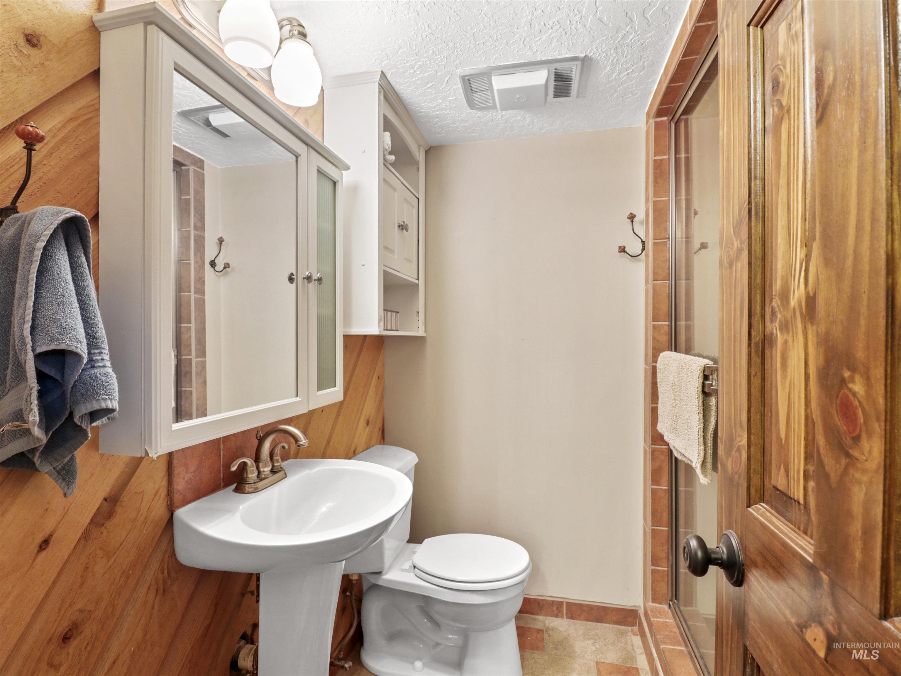 Bathroom with a textured ceiling and a shower