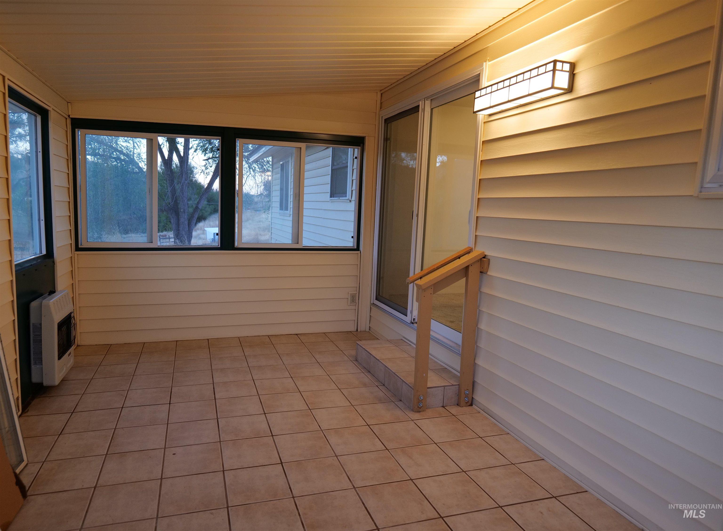 Enclosed sunroom featuring light-toned tile flooring, horizontal vinyl siding, and multiple windows