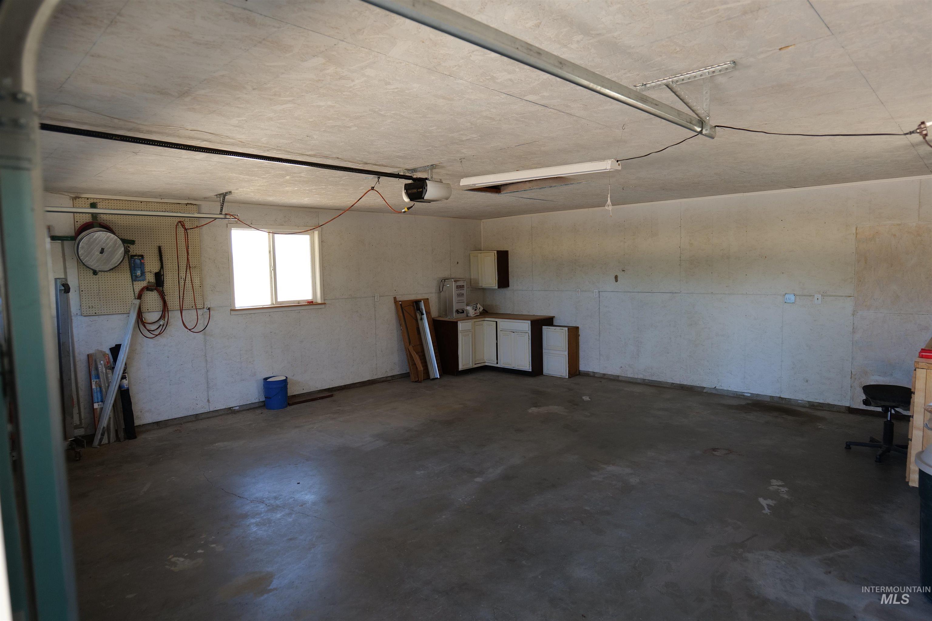 Spacious garage featuring concrete flooring, built-in cabinetry, and a double-paned window for natural light