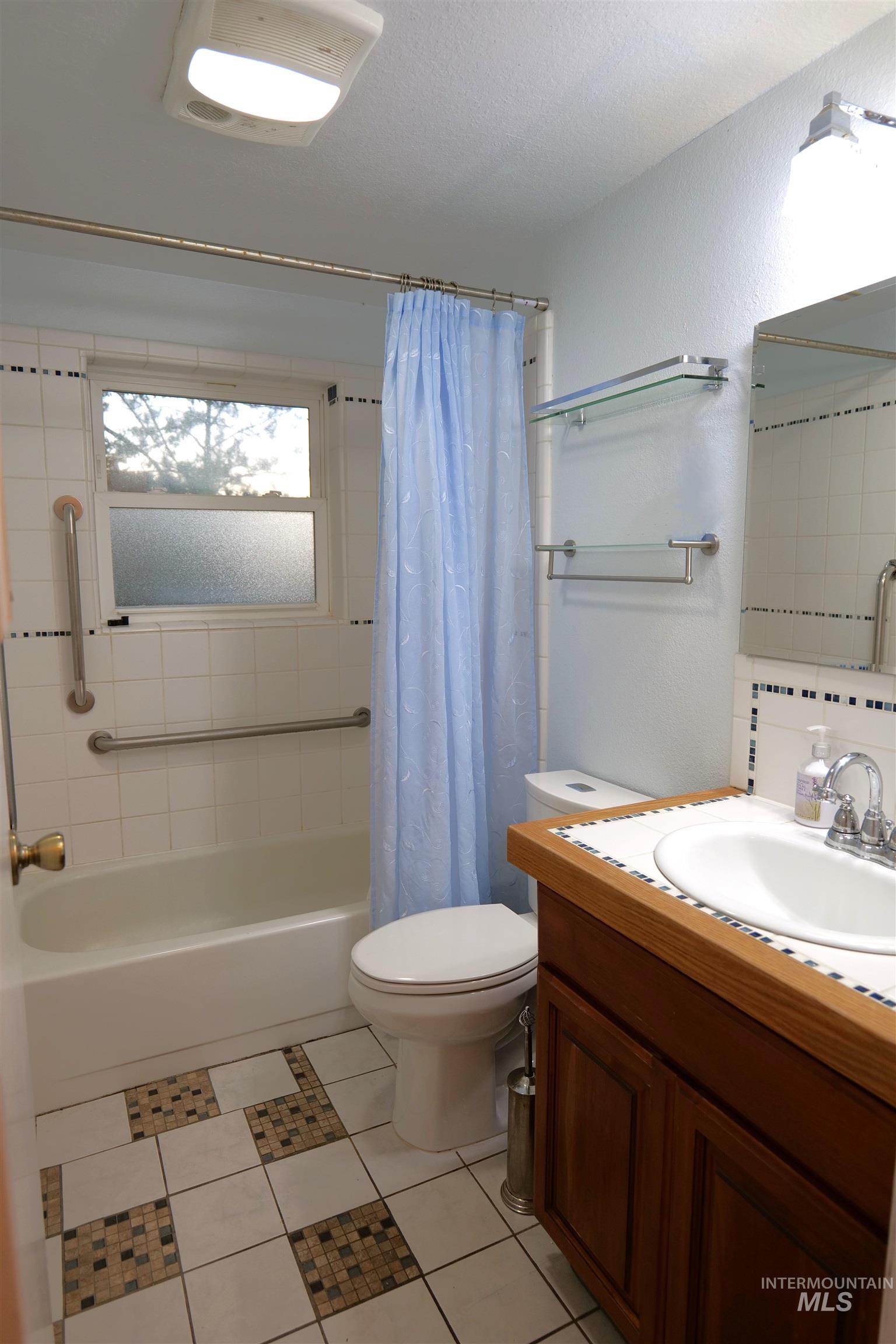 Bathroom featuring a white tub, white tiled walls with accent trim, and a window with frosted glass