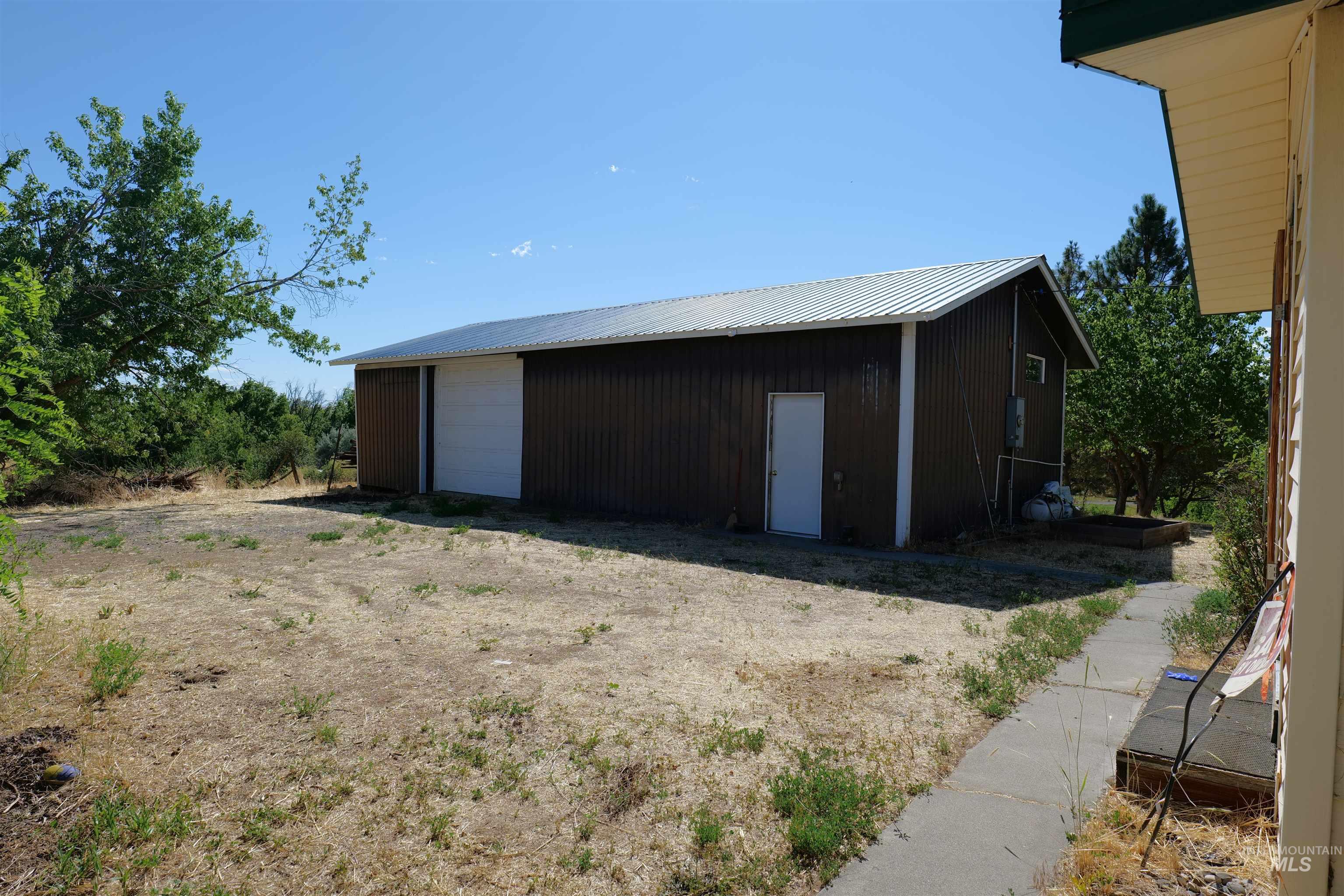 Metal utility building with a white roll-up door, side entry door, and corrugated metal roof