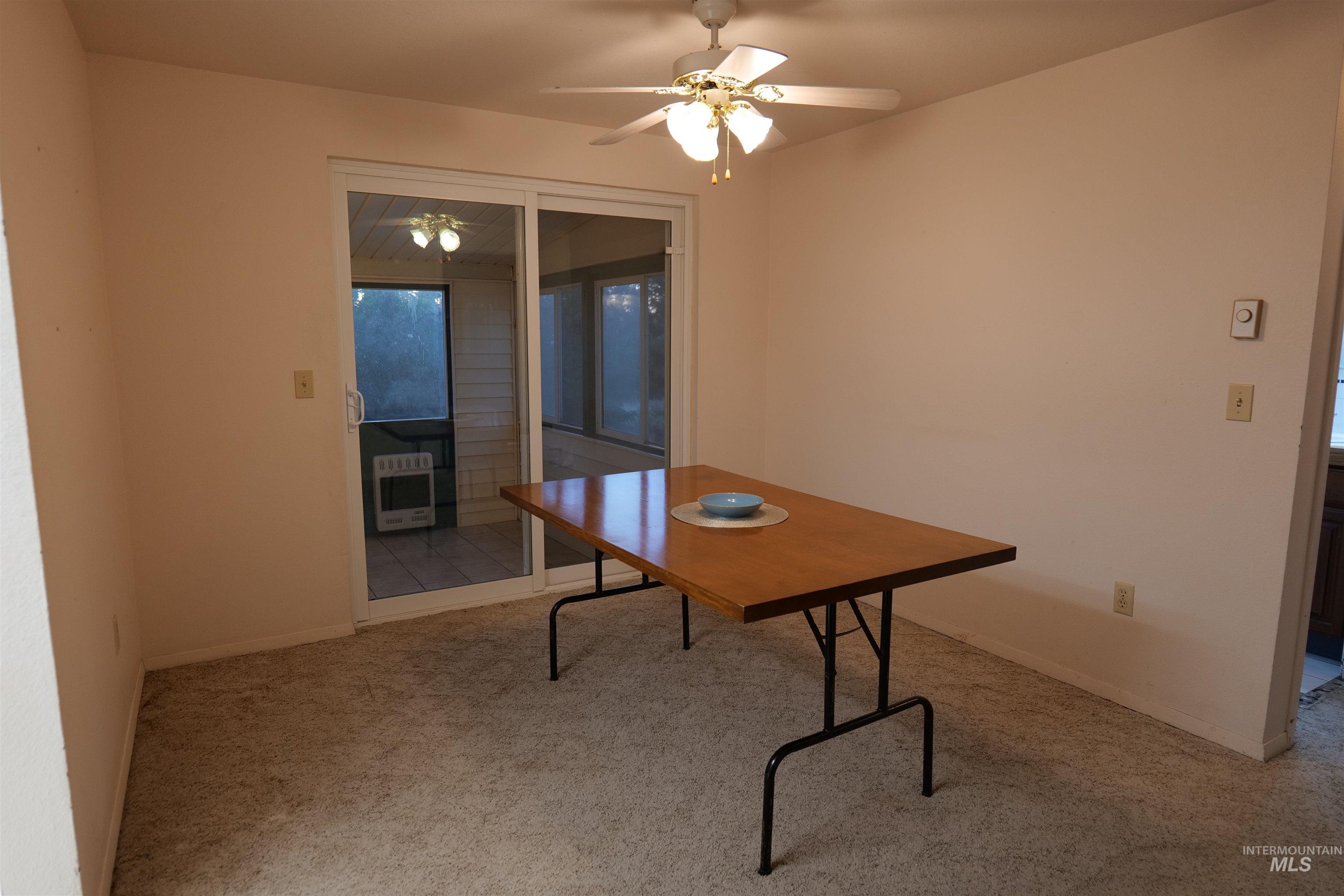 Interior room featuring neutral-toned walls, light-colored carpet, and a ceiling fan with integrated lighting