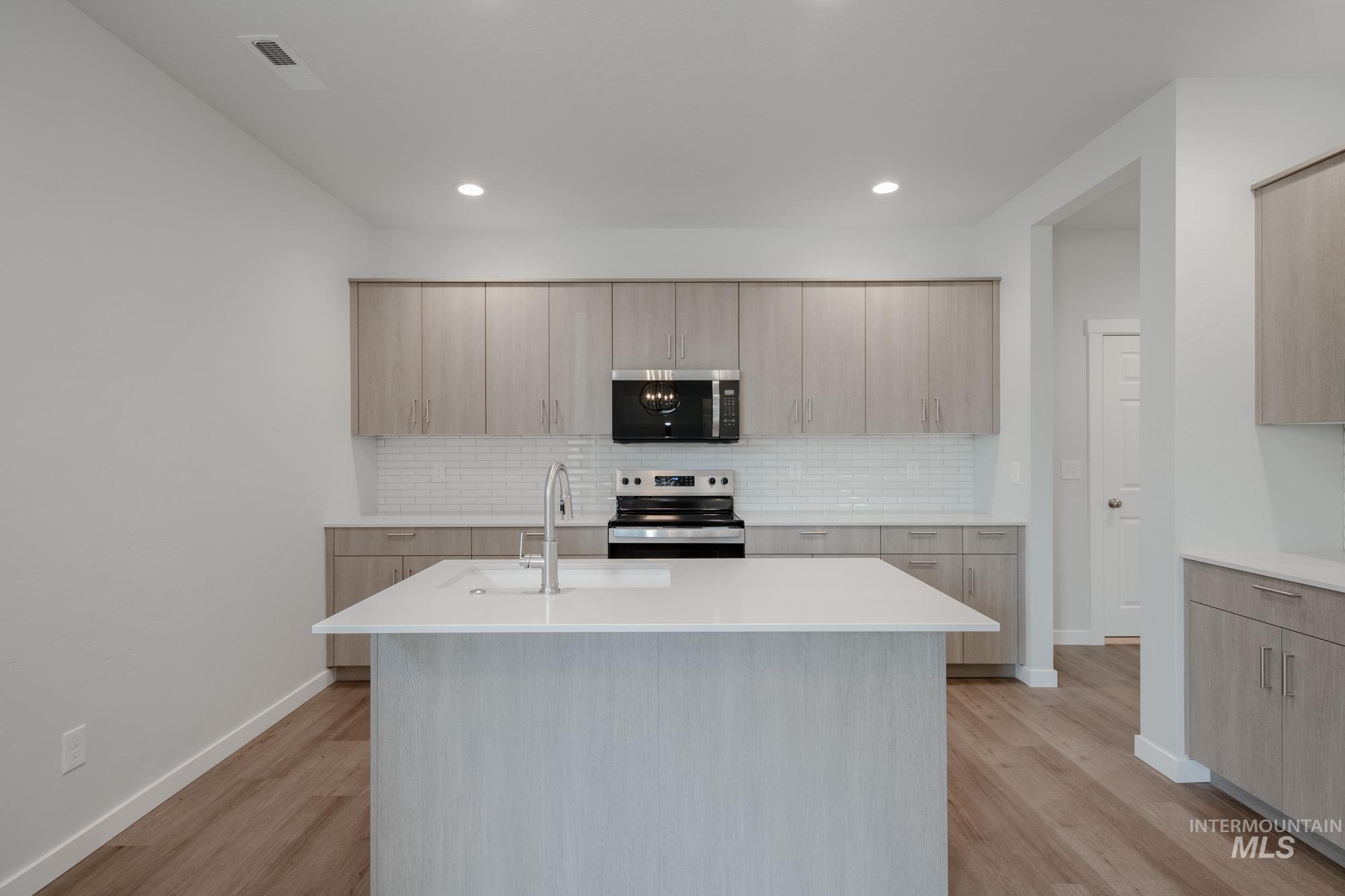 Kitchen featuring tasteful backsplash, a kitchen island with sink, appliances with stainless steel finishes, light brown cabinetry, and recessed lighting