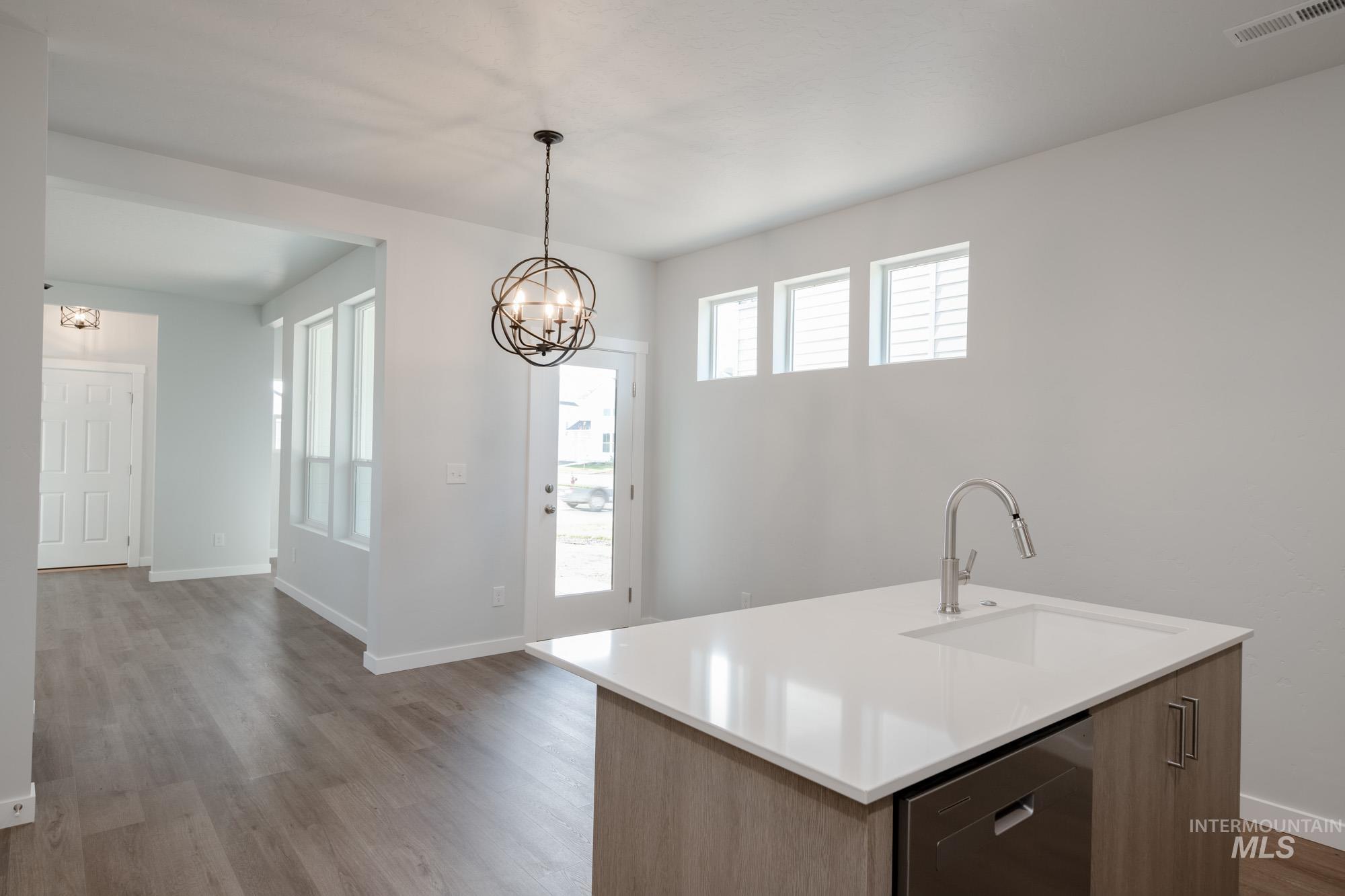 Kitchen featuring light wood finished floors, modern cabinets, a chandelier, pendant lighting, and dishwasher