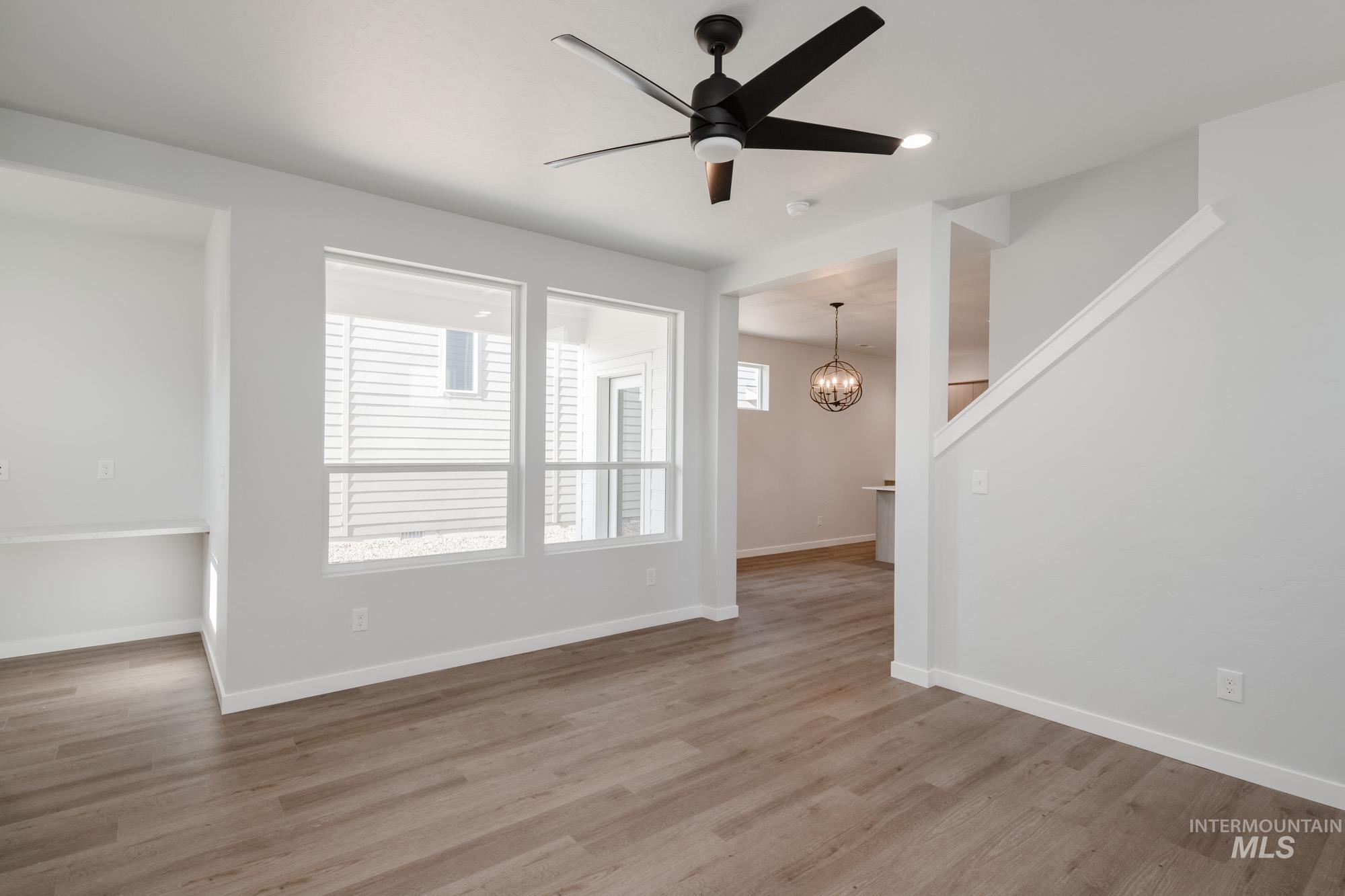 Unfurnished living room featuring wood finished floors, ceiling fan, a chandelier, and recessed lighting