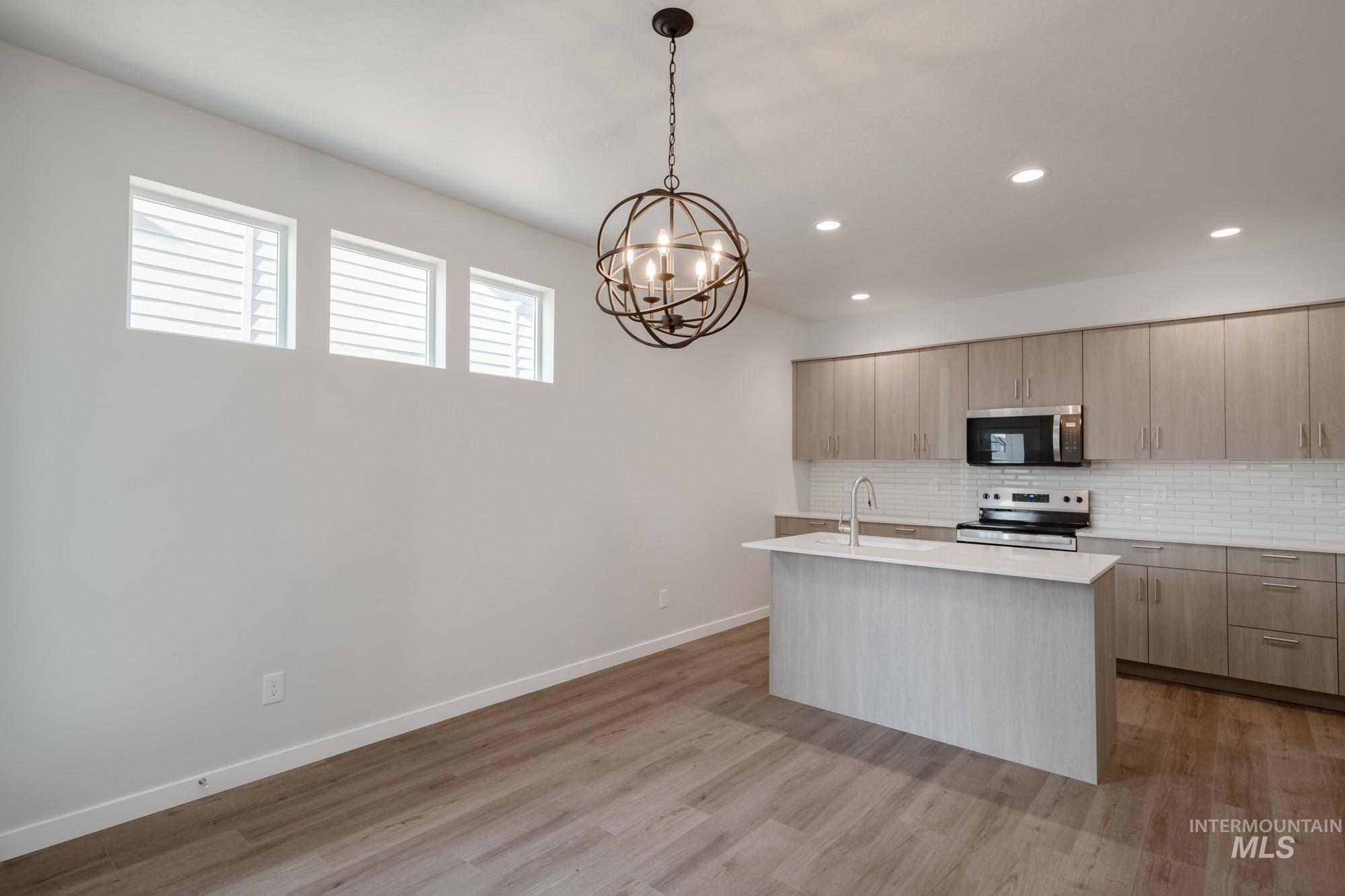 Kitchen with stainless steel appliances, backsplash, an island with sink, pendant lighting, and recessed lighting