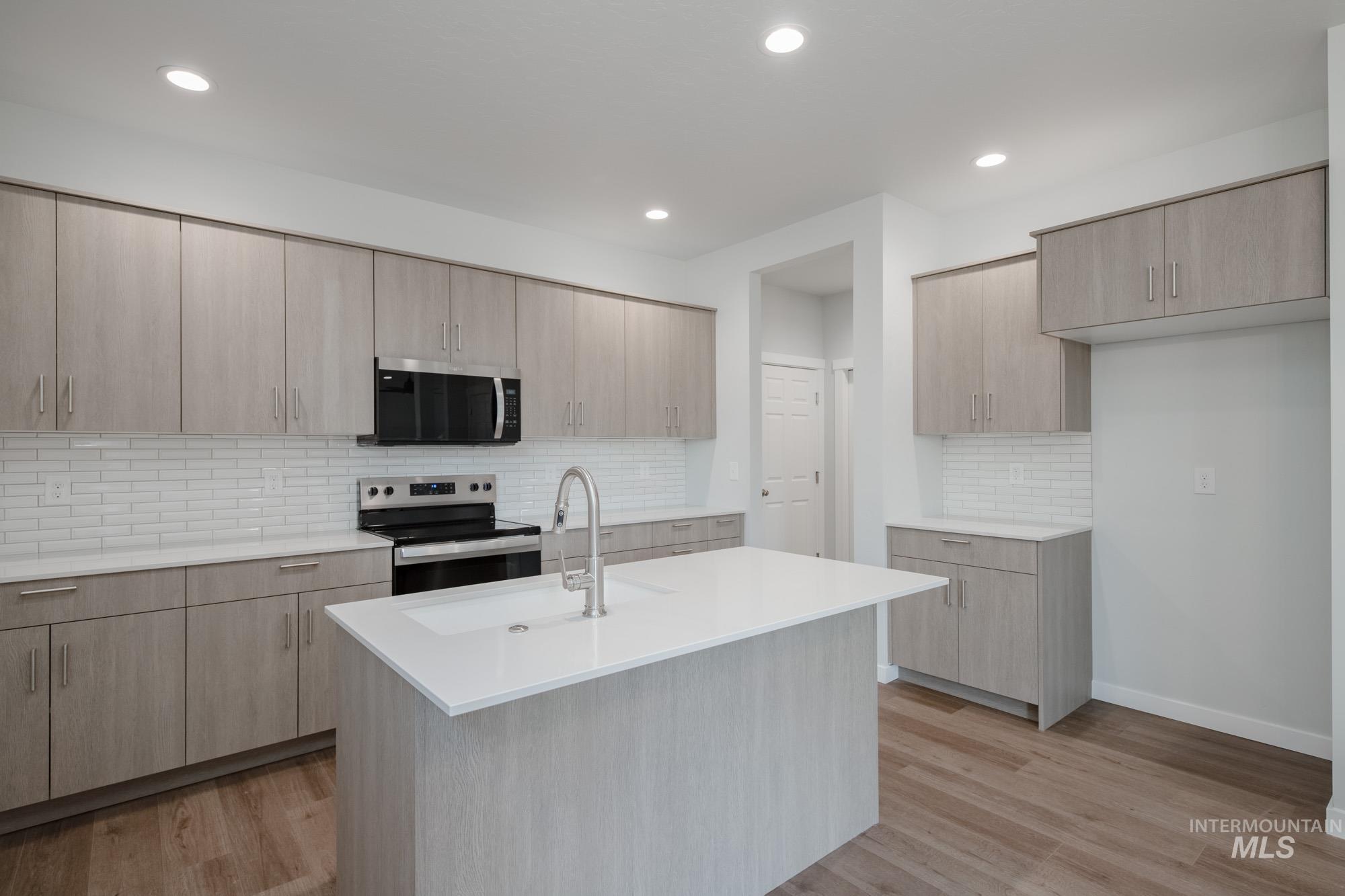 Kitchen featuring light brown cabinetry, tasteful backsplash, stainless steel appliances, modern cabinets, and recessed lighting