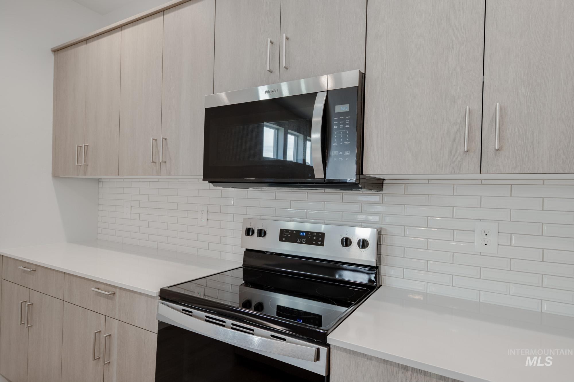 Kitchen featuring light brown cabinets, appliances with stainless steel finishes, modern cabinets, and backsplash