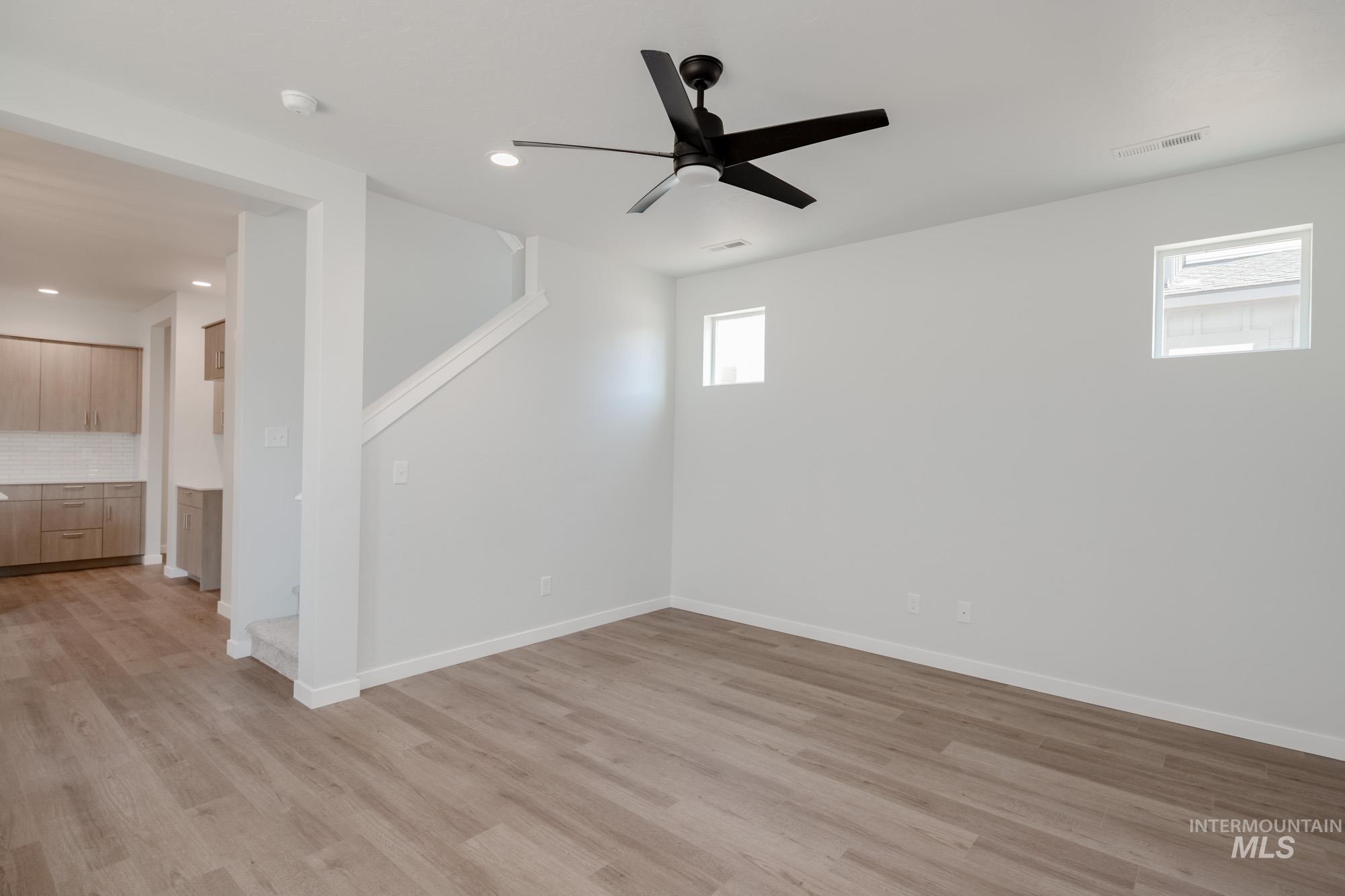 Basement with light wood-type flooring, a ceiling fan, recessed lighting, and stairway