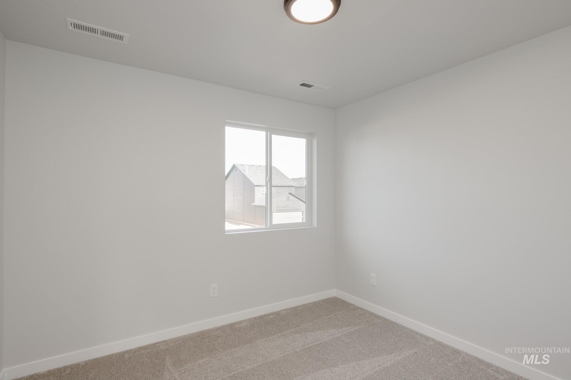 Carpeted spare room featuring baseboards