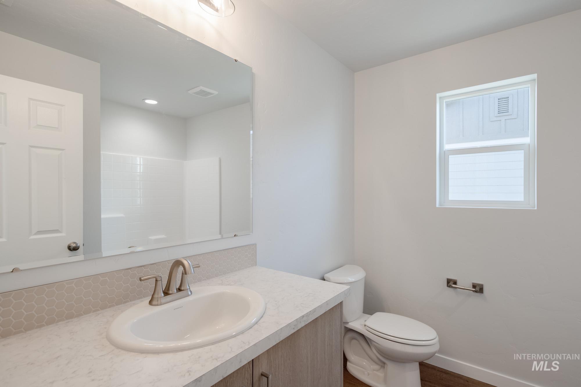 Full bath with vanity and dark wood-type flooring