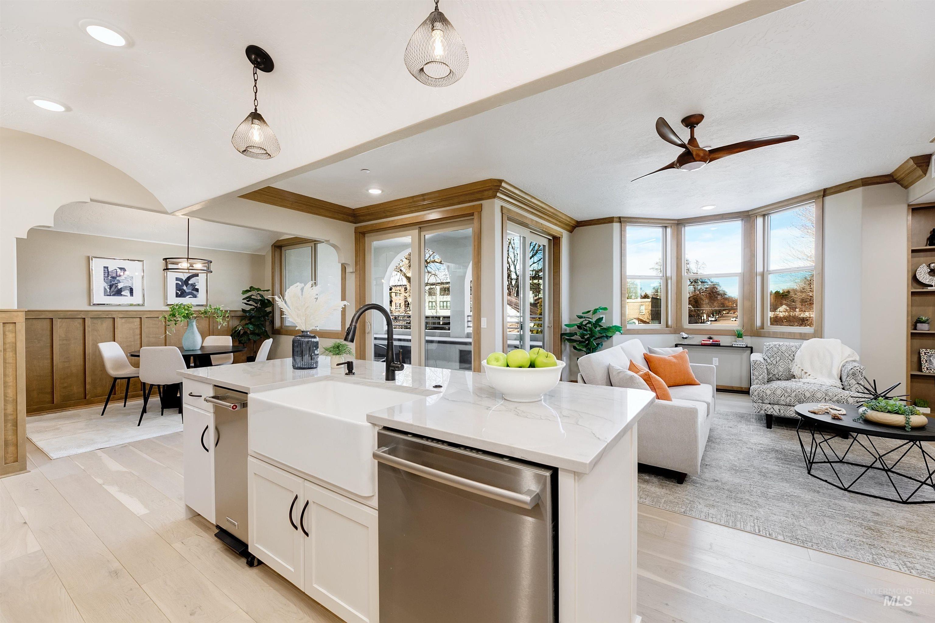 Kitchen with open floor plan, dishwasher, pendant lighting, white cabinetry, and light stone counters
