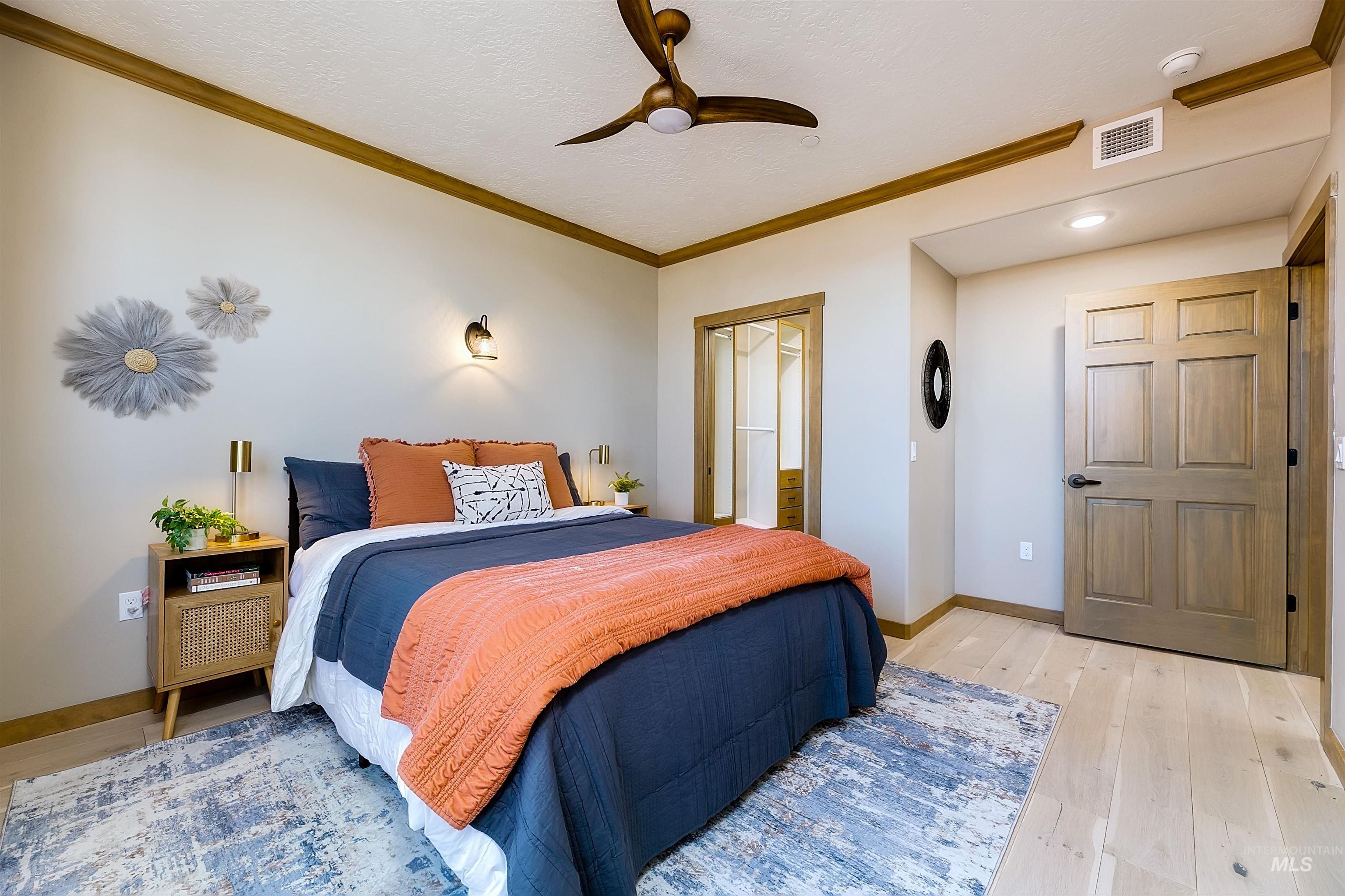 Bedroom featuring crown molding, light wood-style floors, ceiling fan, and a textured ceiling
