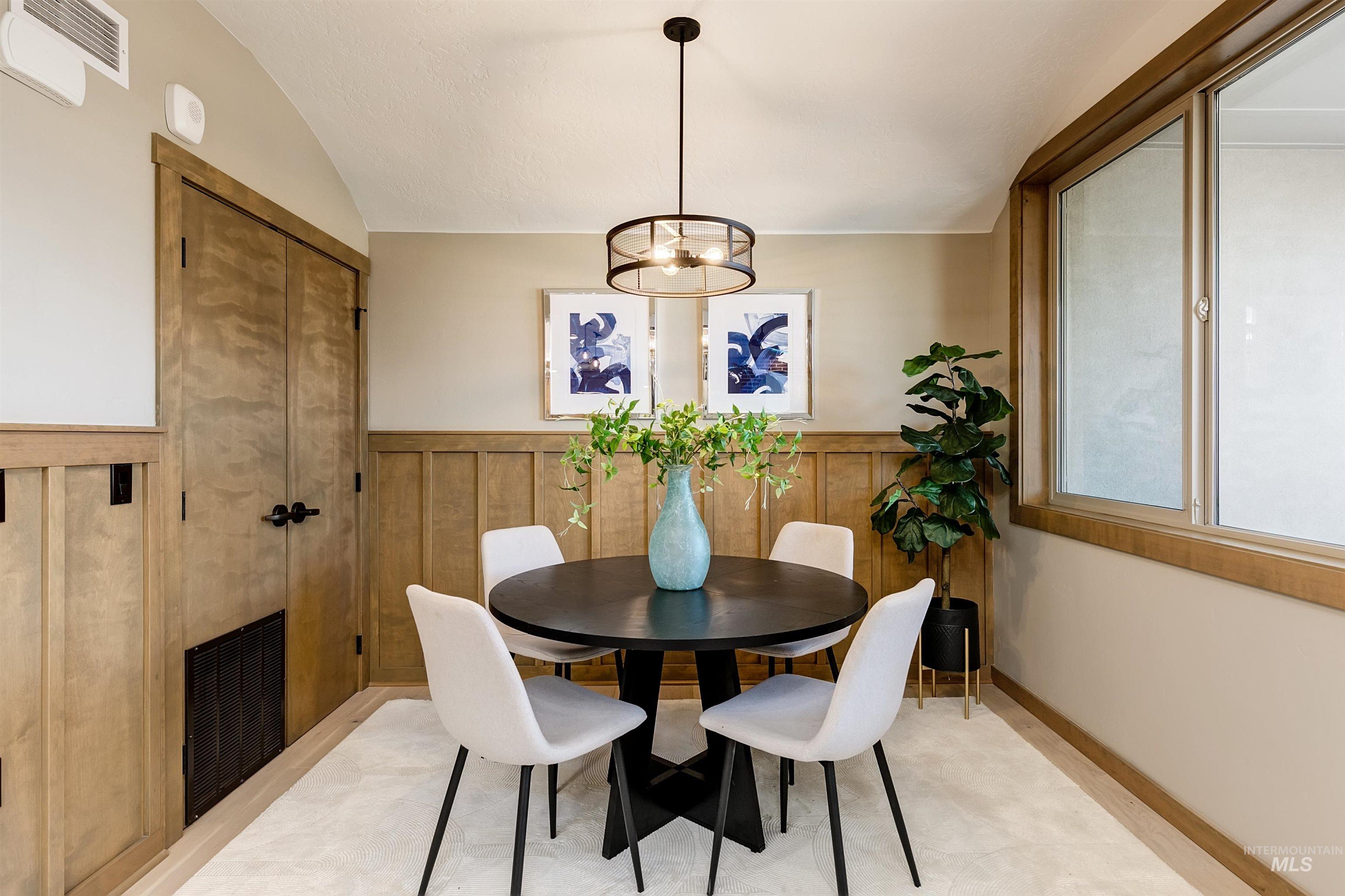 Dining area featuring lofted ceiling and a wainscoted wall