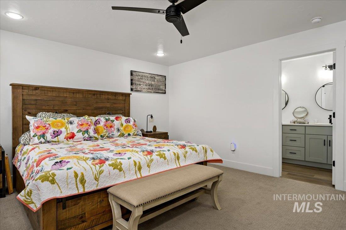 Carpeted bedroom featuring a ceiling fan, ensuite bathroom, and recessed lighting