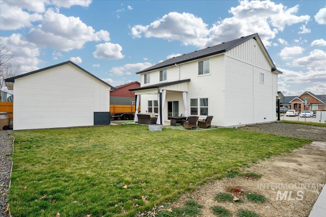 Rear view of property featuring a patio, a lawn, board and batten siding, and outdoor lounge area