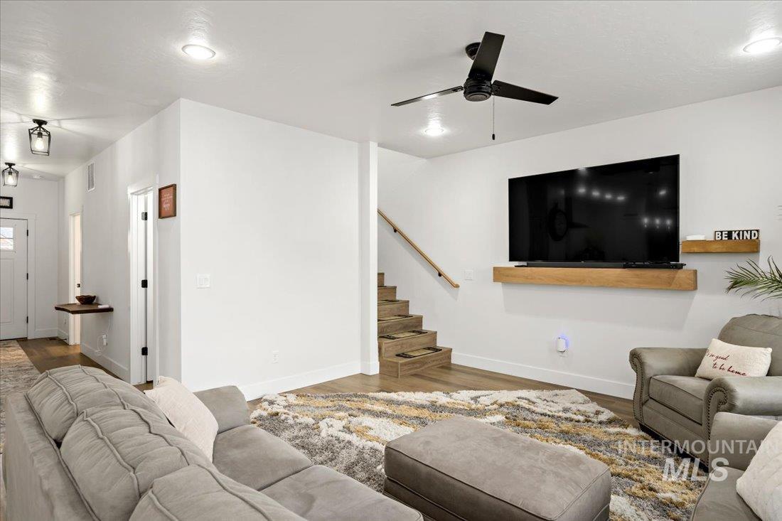 Living area featuring wood finished floors, ceiling fan, recessed lighting, and stairs