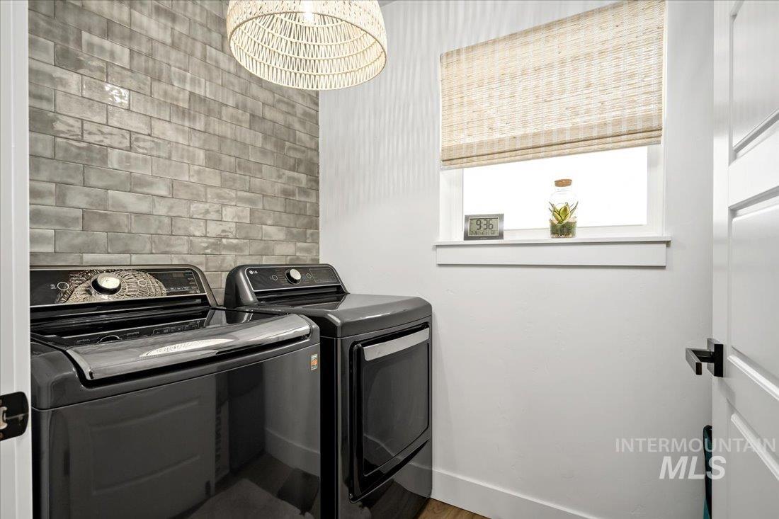 Laundry area with washer and dryer, wood finished floors, and a chandelier