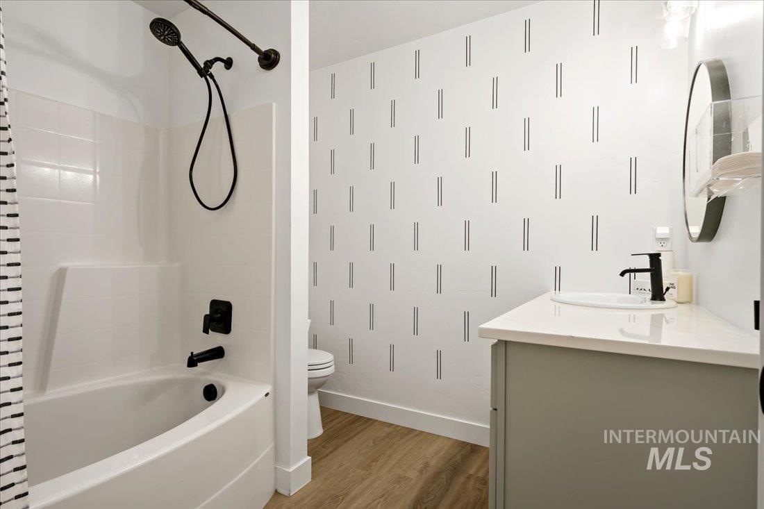 Full bathroom with vanity, shower / bath combination with curtain, and light wood finished floors