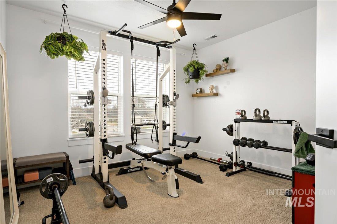 Workout room with light carpet and a ceiling fan