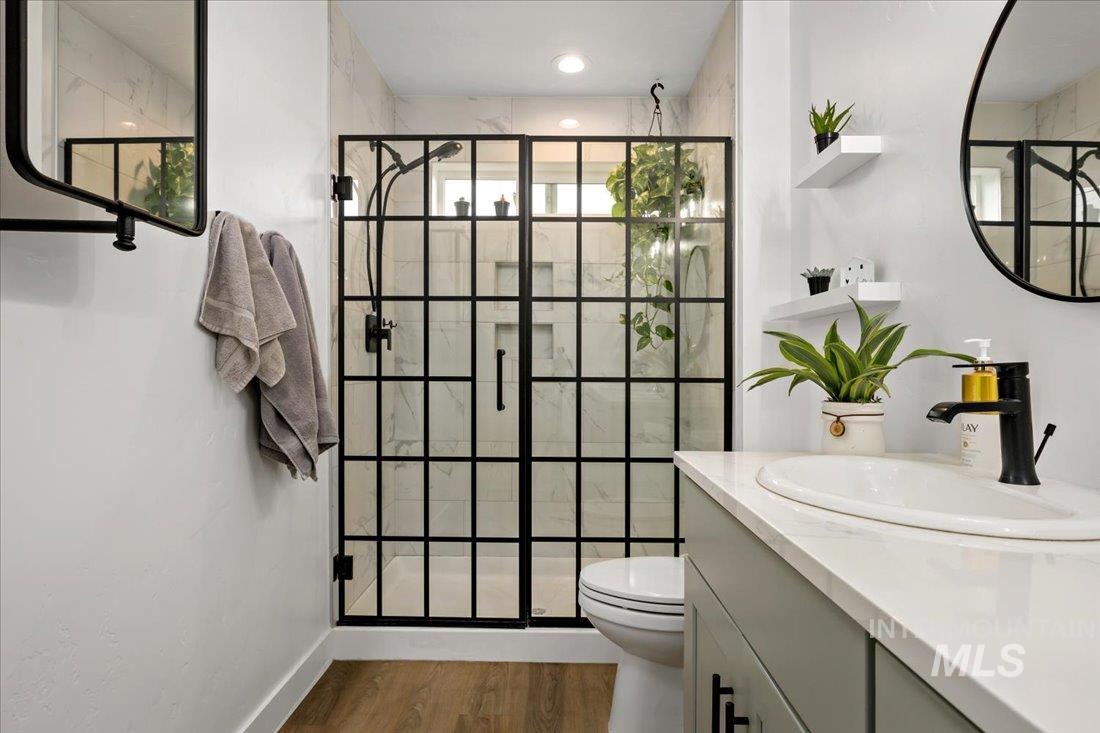 Bathroom with a shower stall, vanity, and dark wood-style flooring