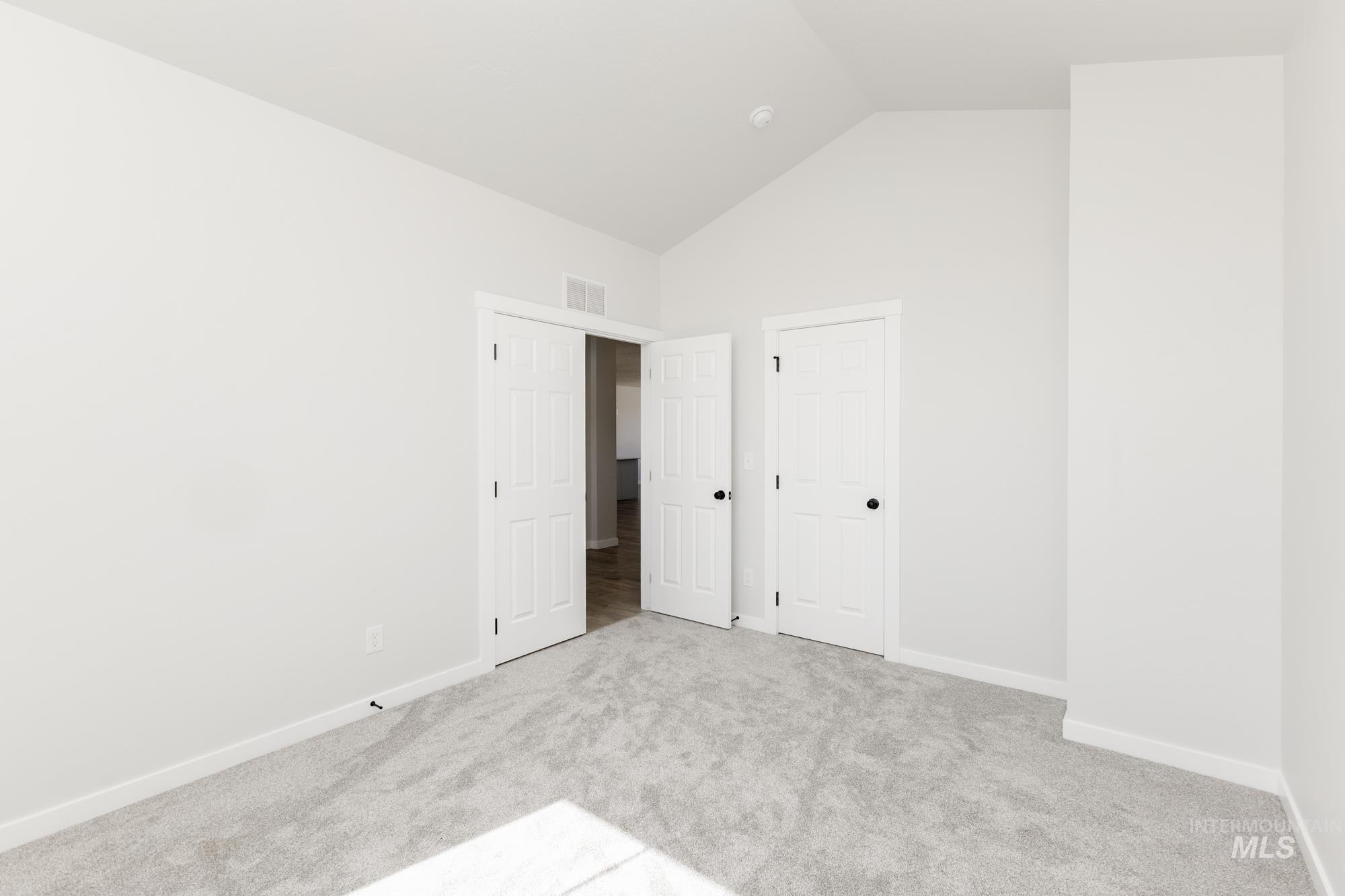 Unfurnished bedroom with carpet and high vaulted ceiling