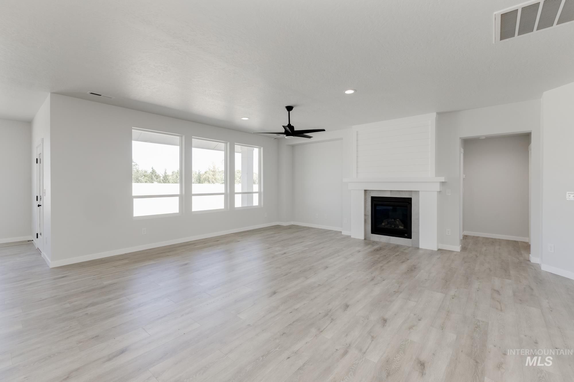 Unfurnished living room featuring a fireplace, ceiling fan, light wood-style flooring, and recessed lighting